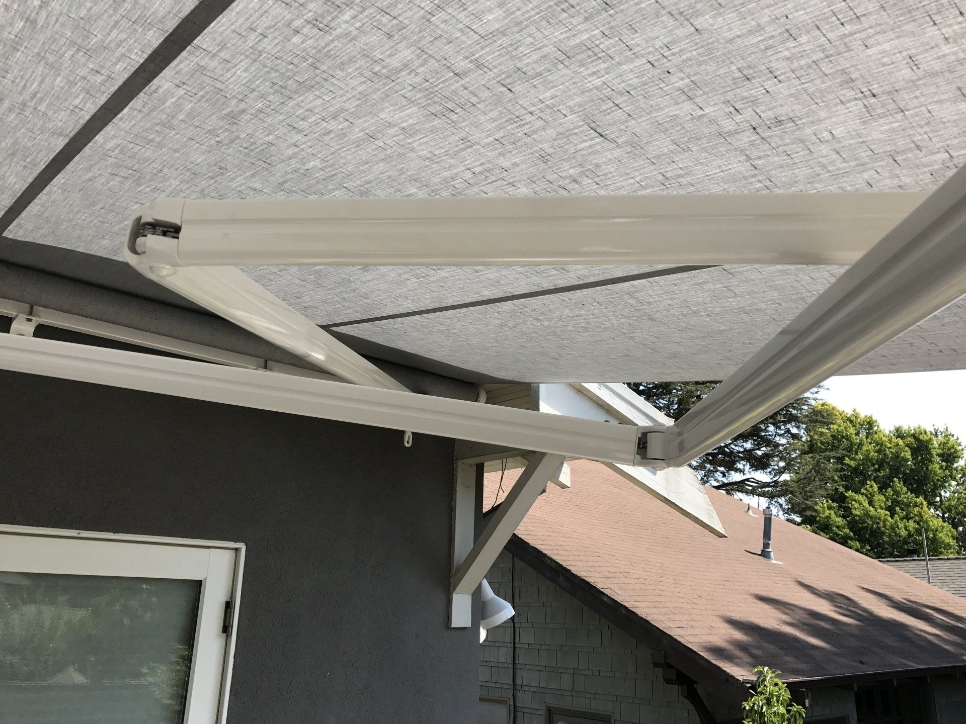 A white awning is hanging from the side of a house.