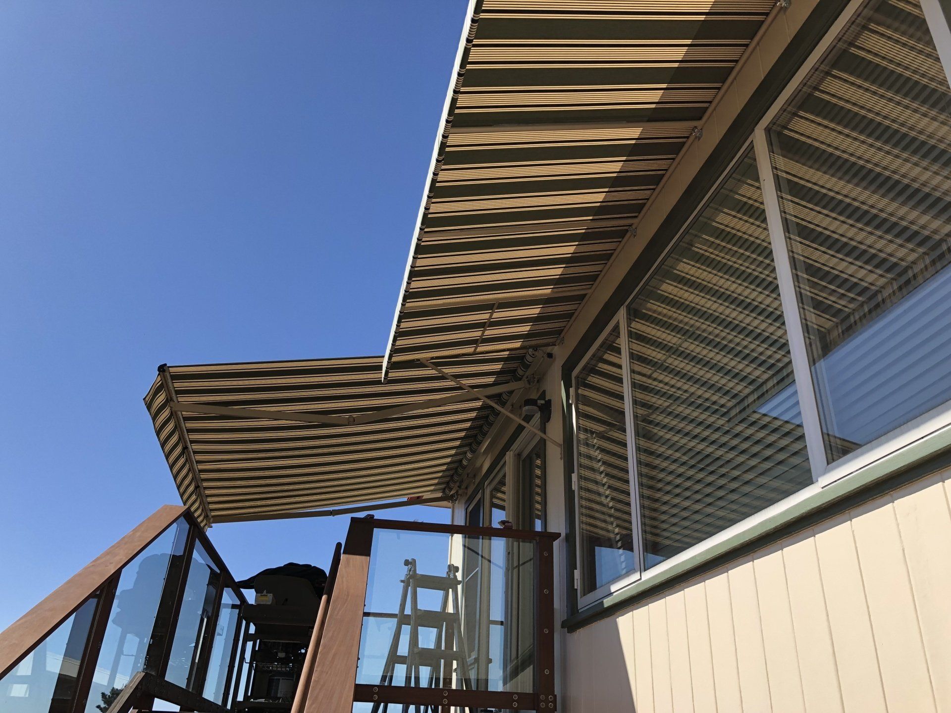 A balcony with a striped awning over it and stairs leading up to it.