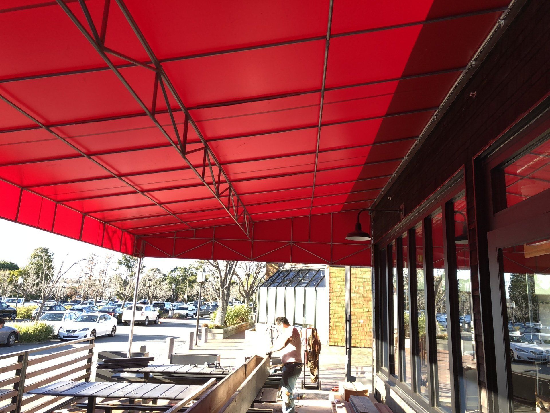 A red awning is over a patio with tables and chairs.