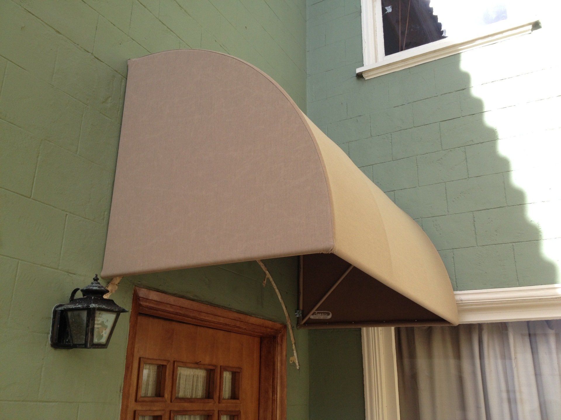 A tan awning hangs over a wooden door