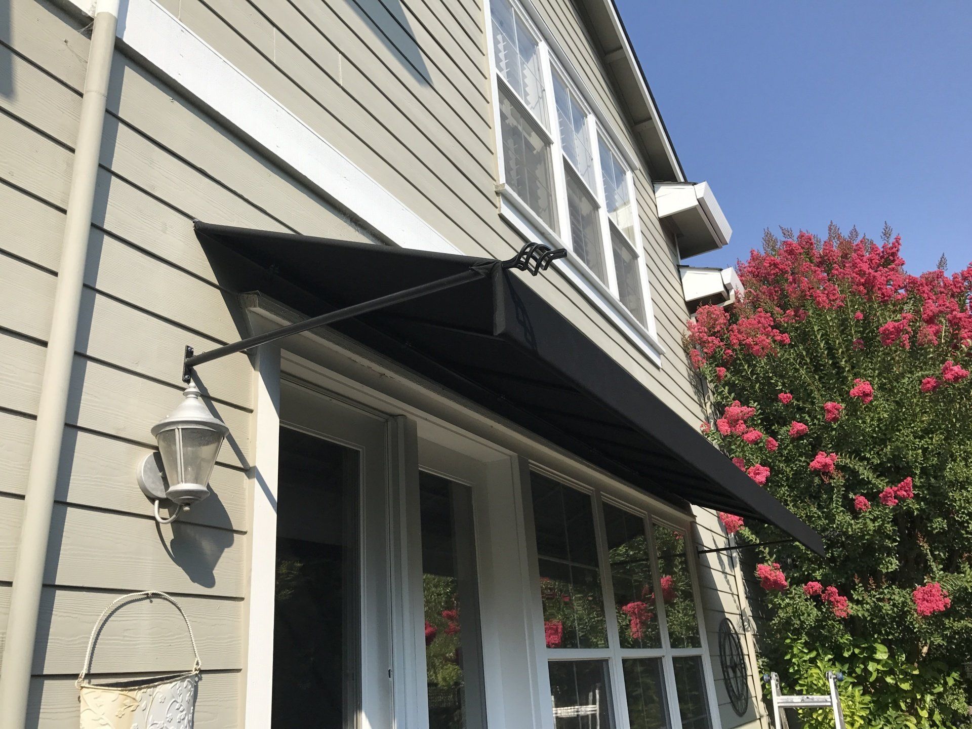 A black awning is on the side of a house.