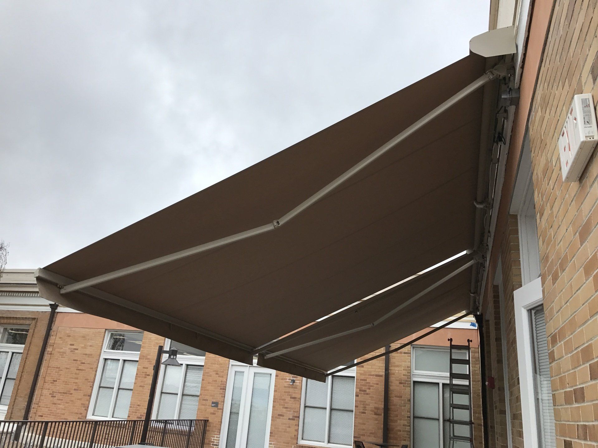 A large awning is hanging from the side of a brick building.