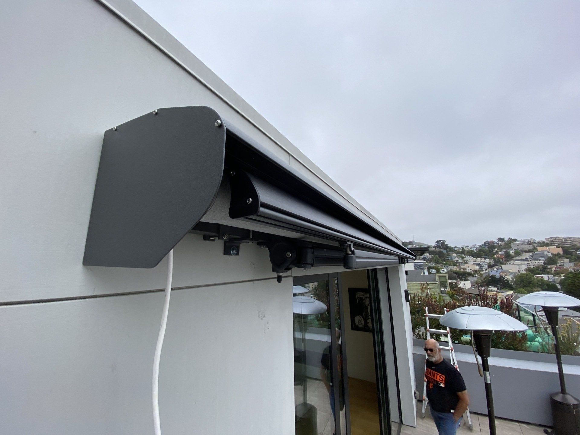 A man is standing under a awning on the side of a building