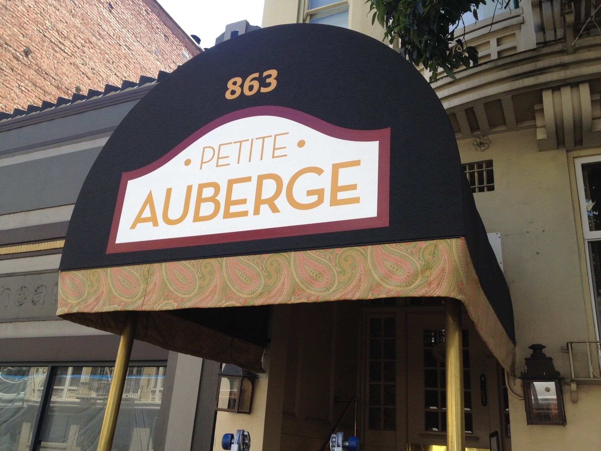A black awning over the entrance to petite auberge