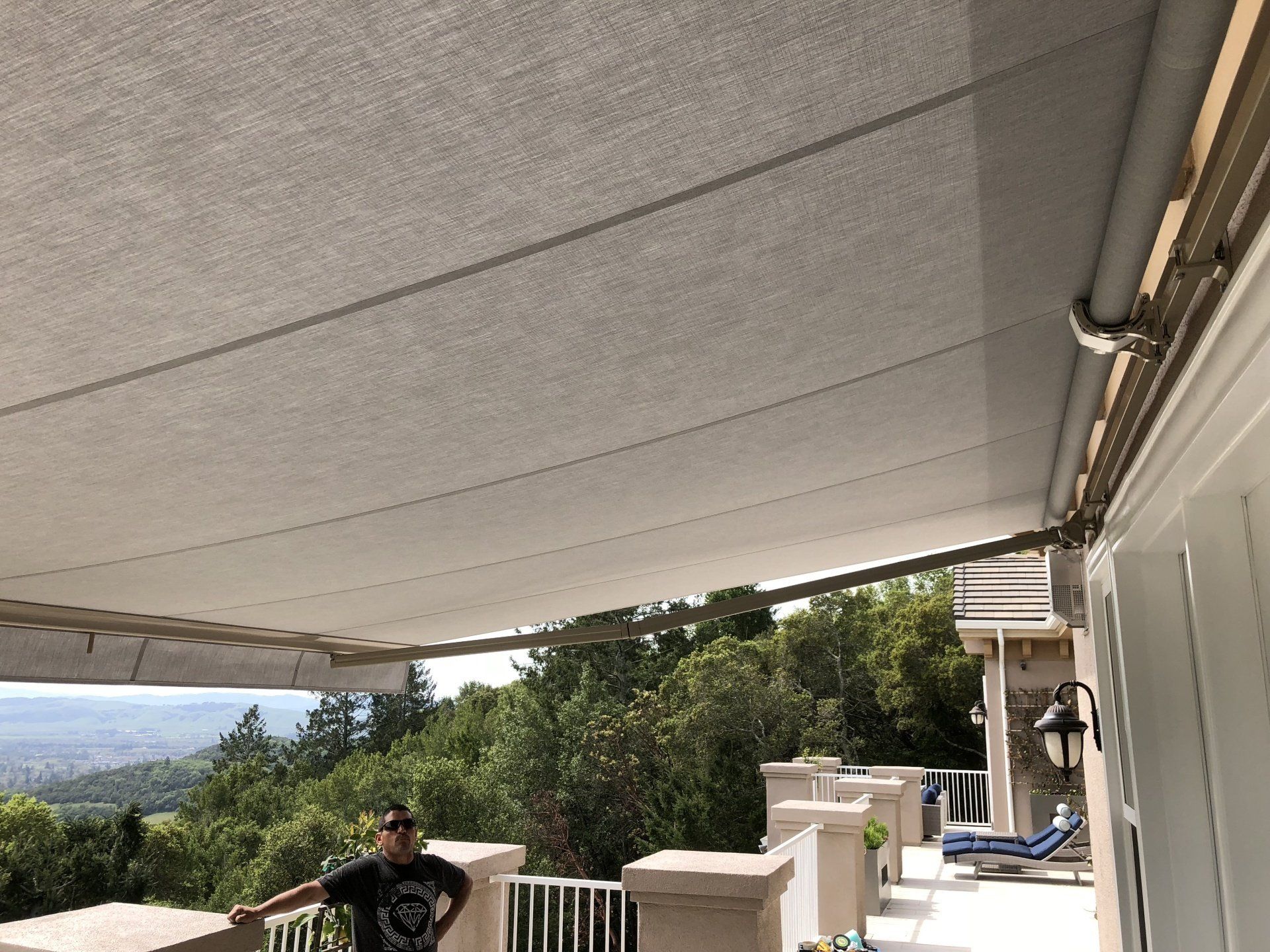 A man is standing under an awning on a balcony.
