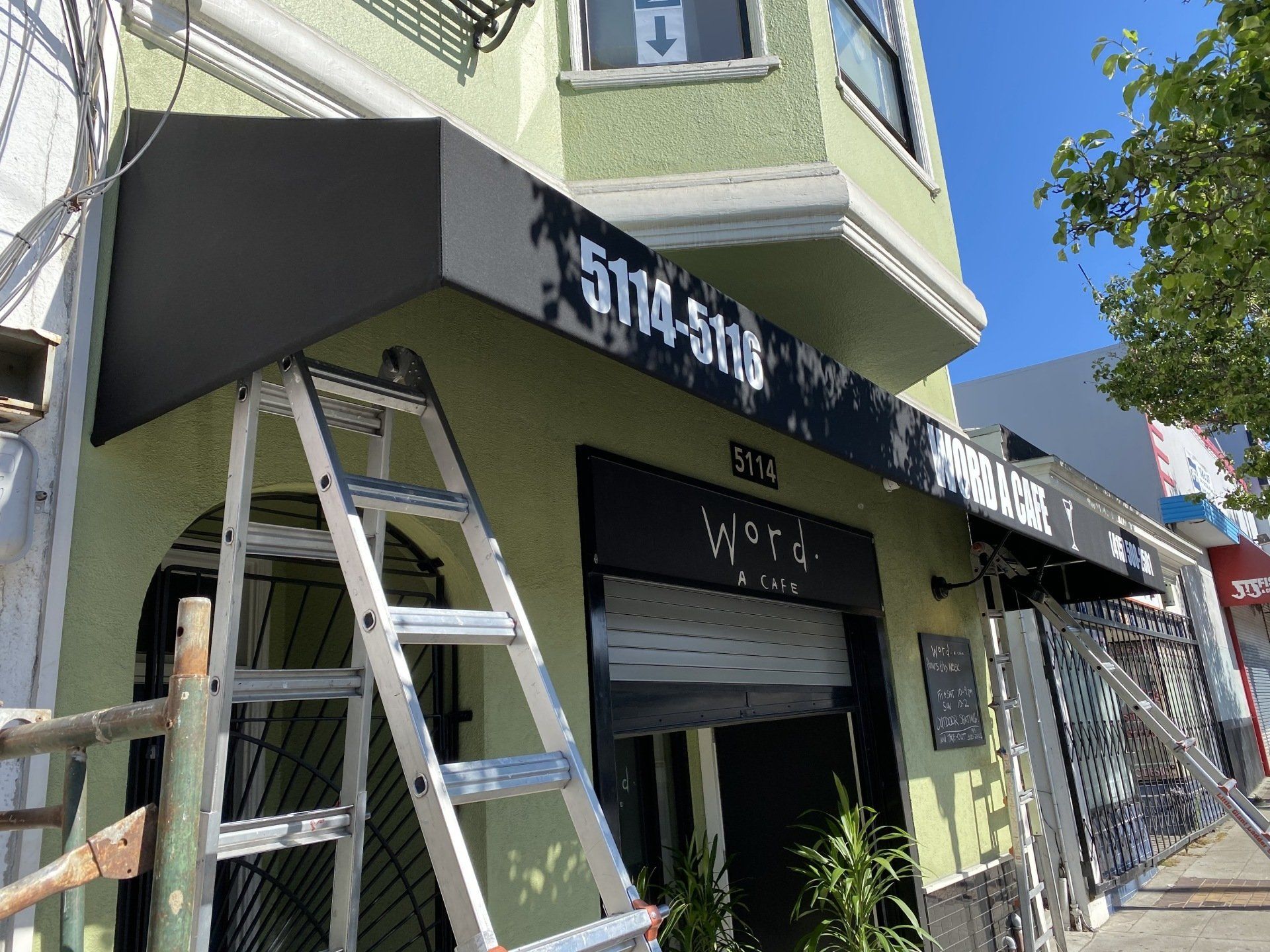 A ladder is sitting on the sidewalk in front of a building.