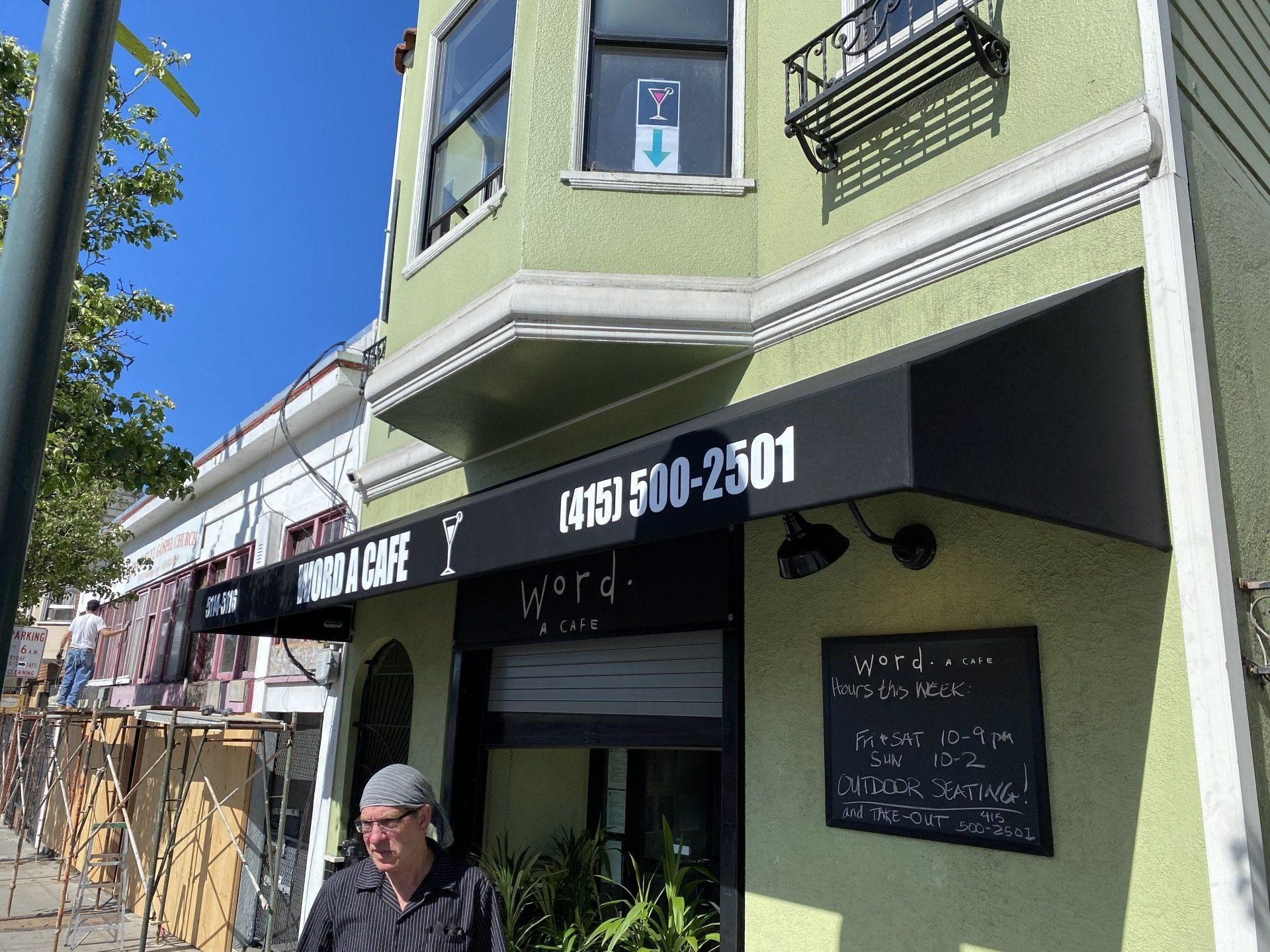 A man standing in front of a building with a phone number on it