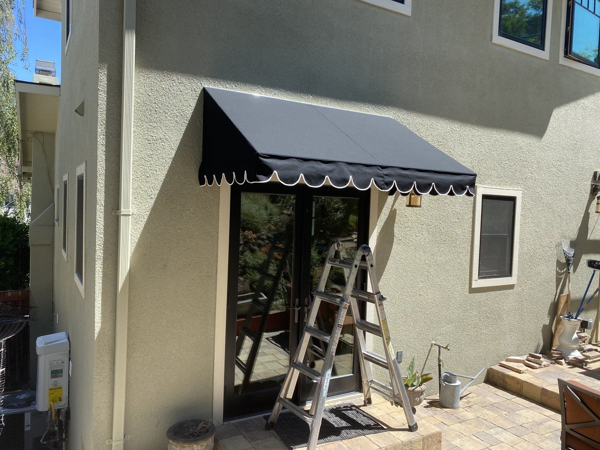 A black awning is being installed on the side of a house