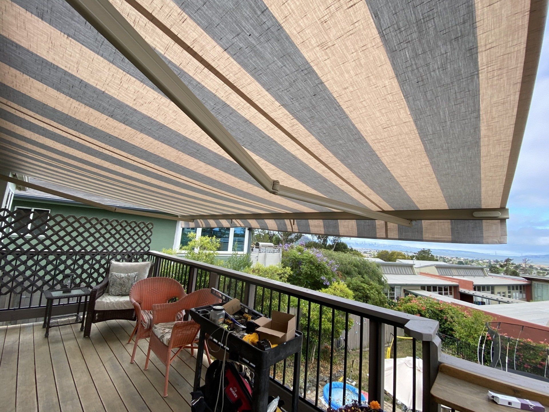A balcony with a striped awning over it and a view of the ocean.