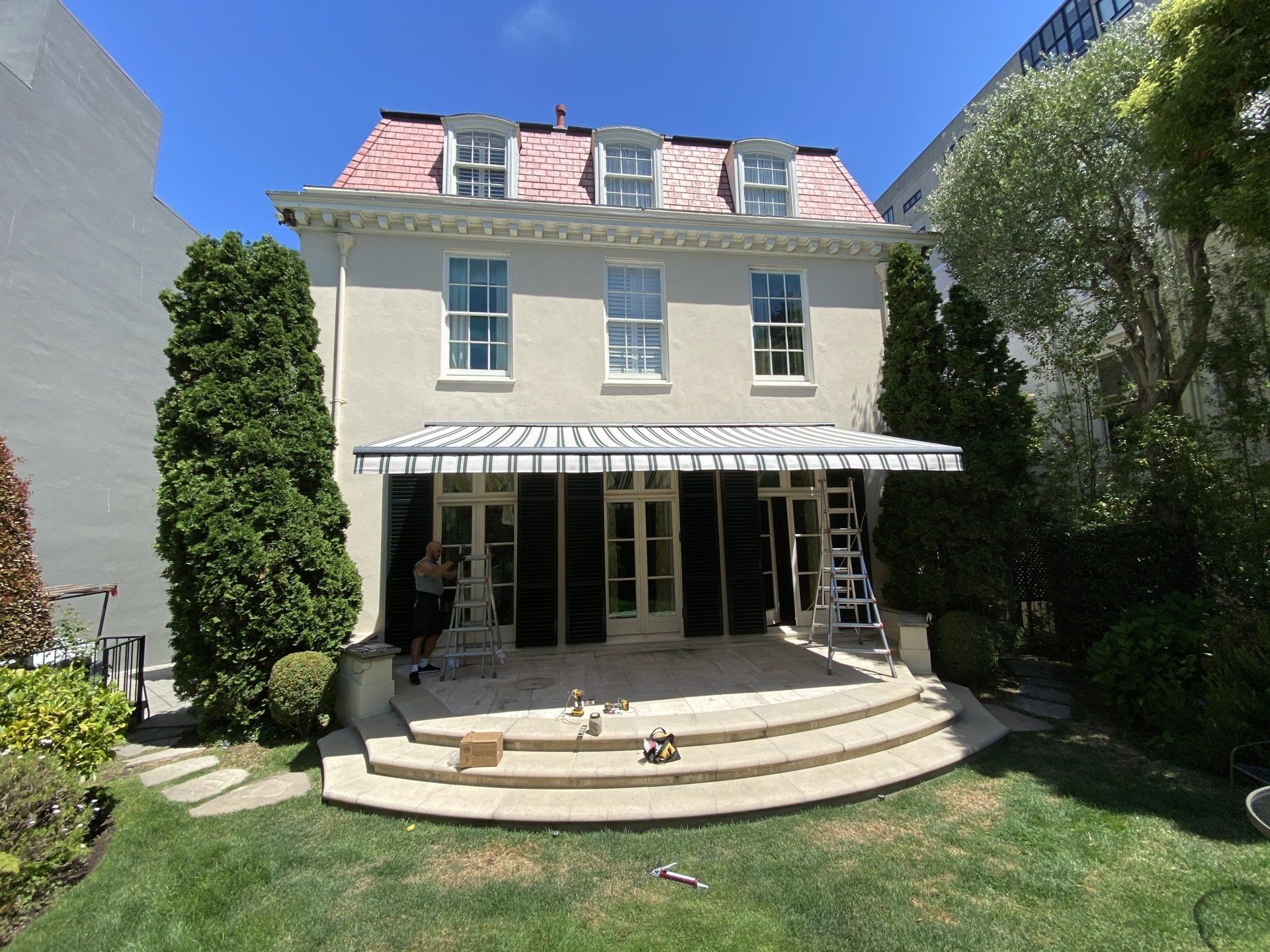 The back of a white house with a pink roof
