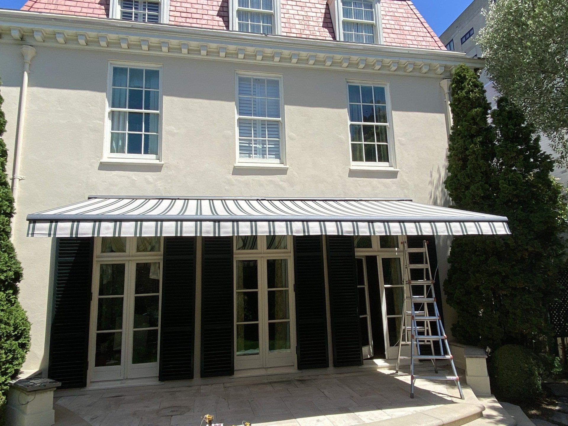 A white house with black shutters and a white awning