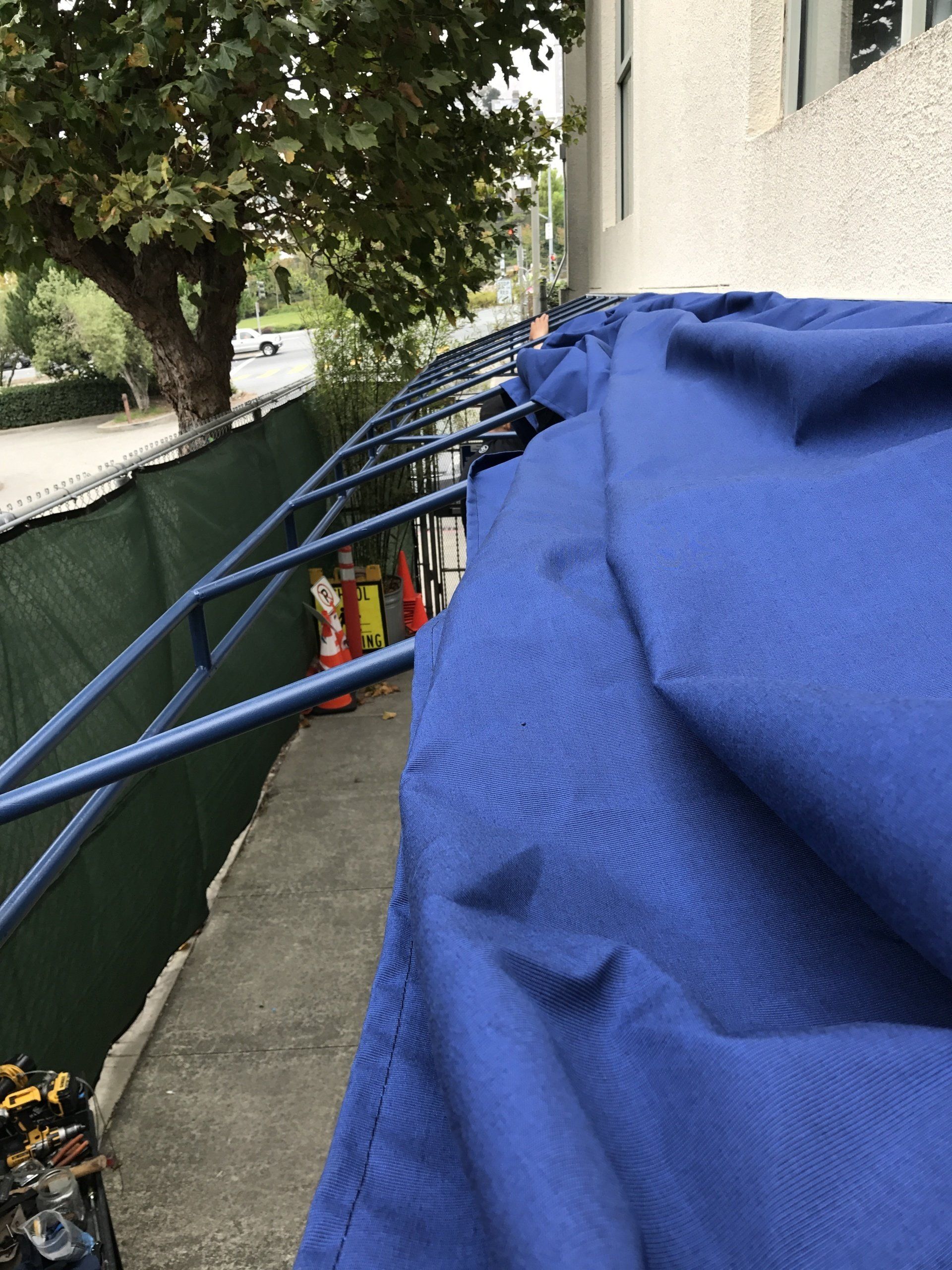 A blue cloth is hanging on a railing next to a building.