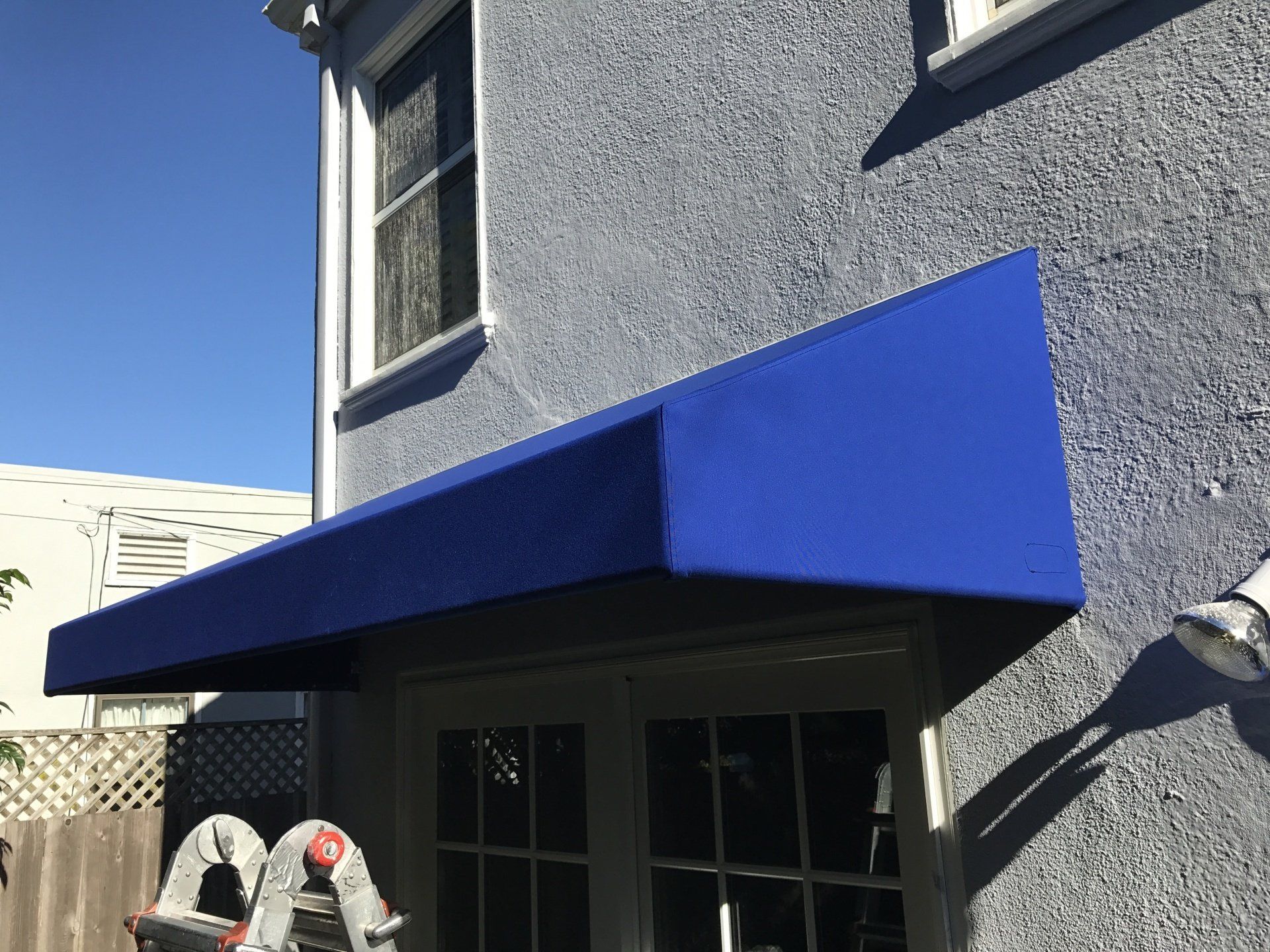 A blue awning is on the side of a building.