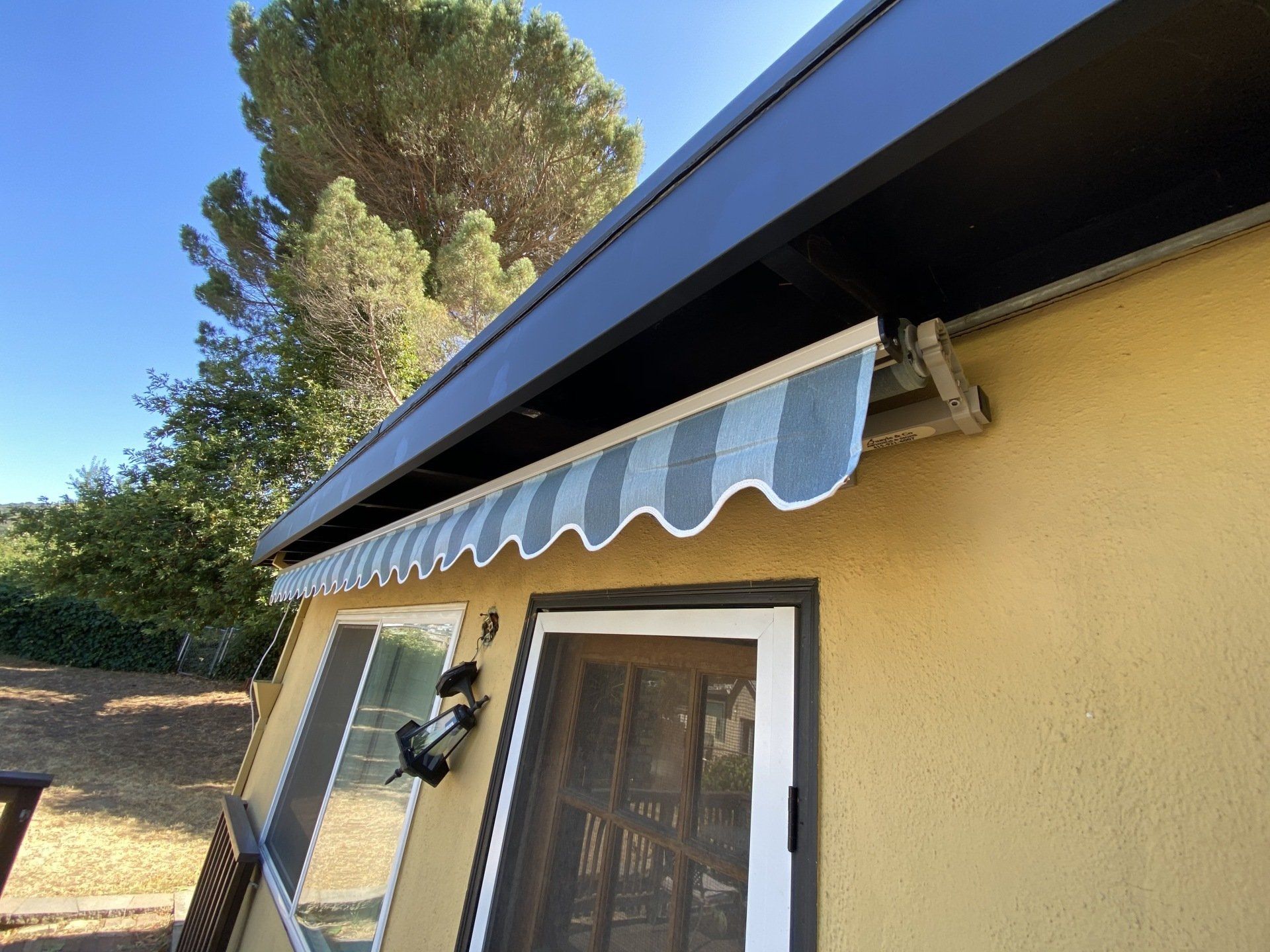 A yellow house with a blue and white awning over the door.