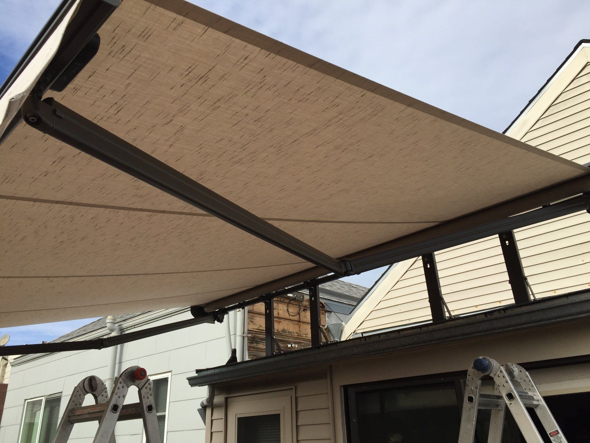 A ladder is sitting under an awning on the side of a building