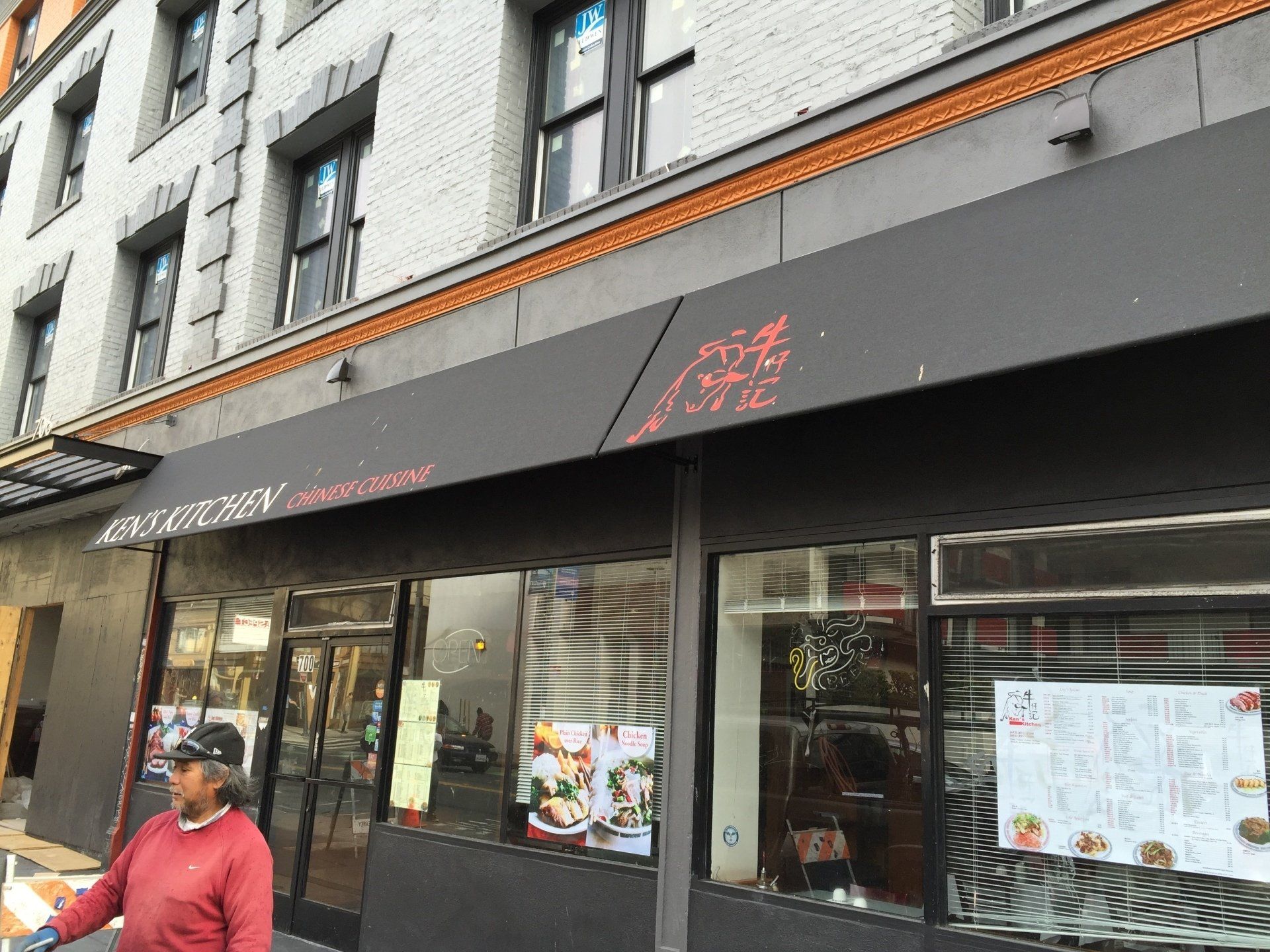 A man standing outside of a restaurant with a black awning