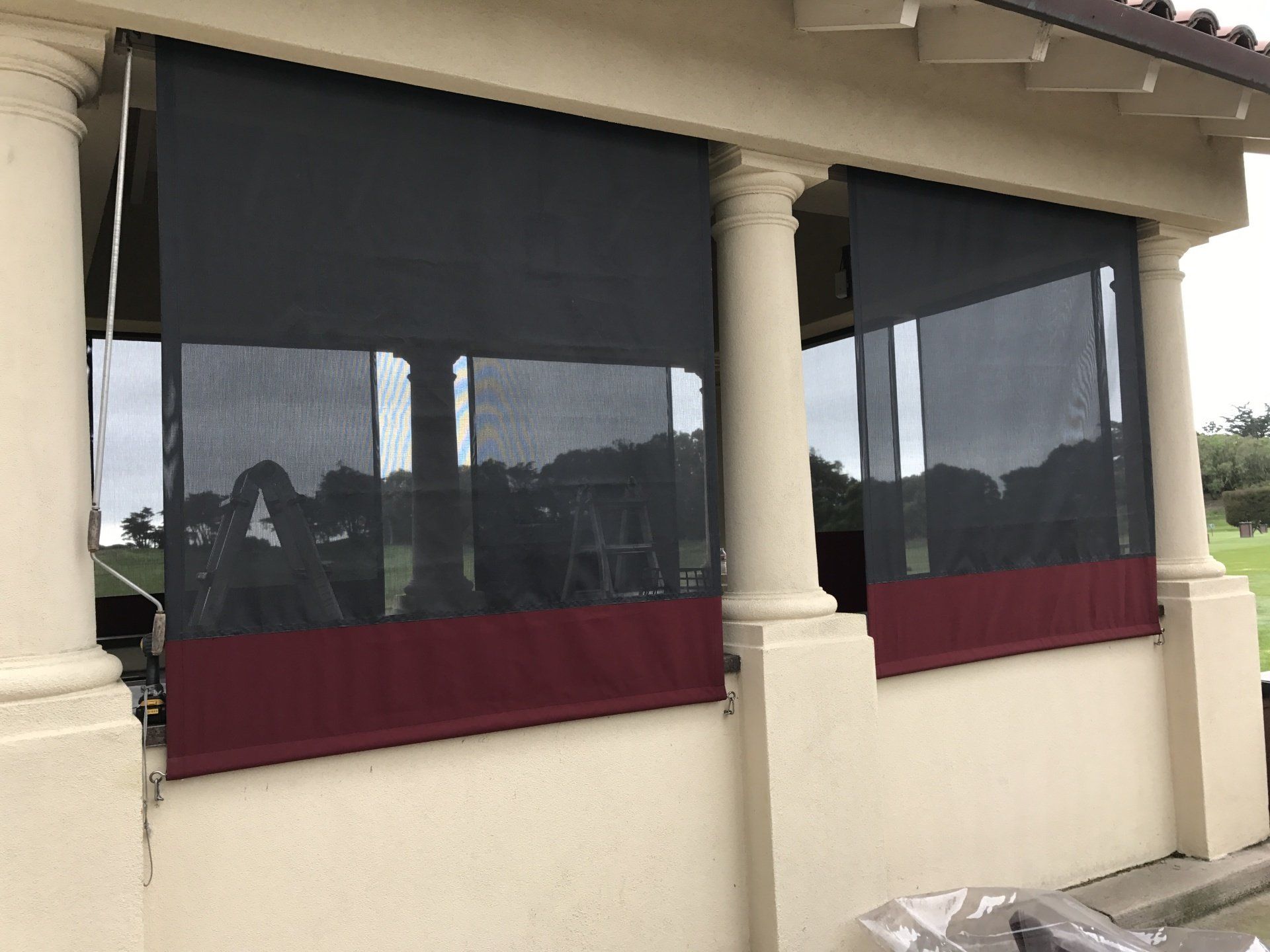 A covered porch with a black and red awning on the windows.