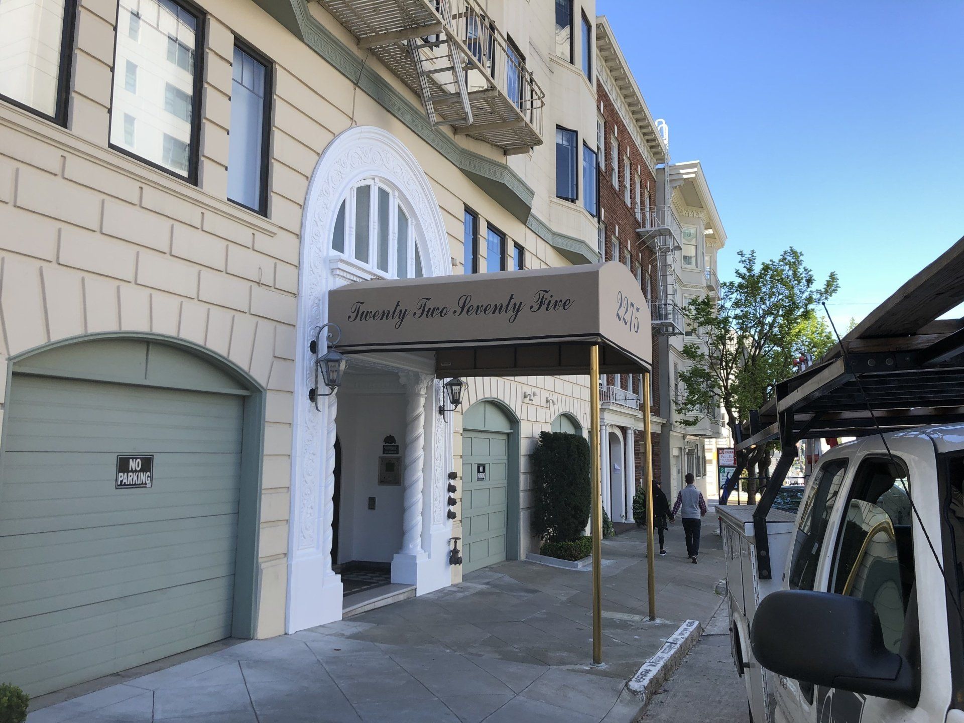 A white truck is parked in front of a building with a canopy over the entrance