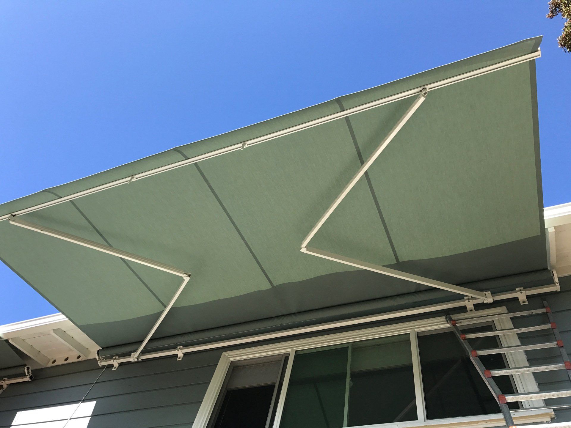A gray house with a green awning over a window