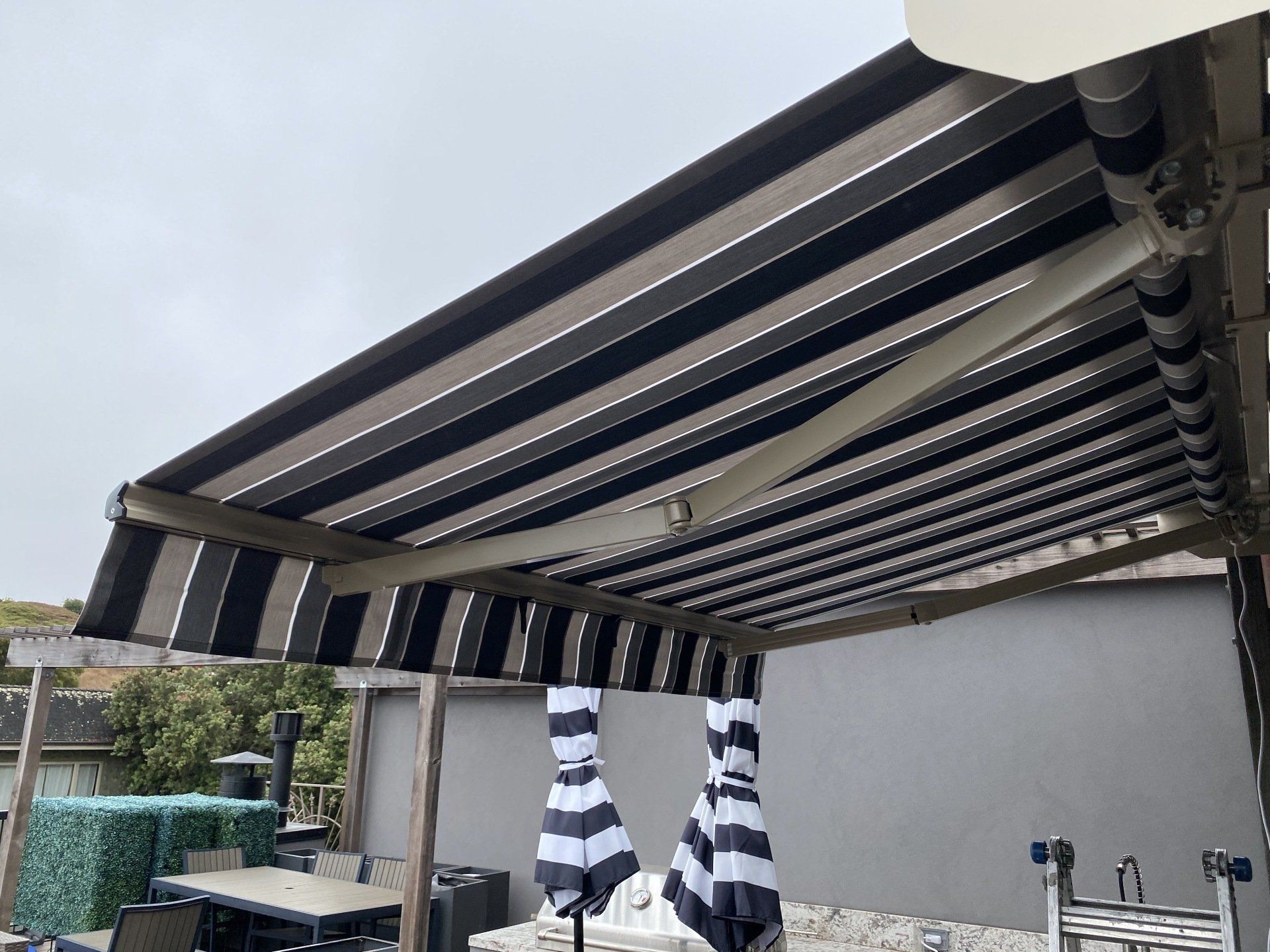 A black and white striped awning is covering a patio area.