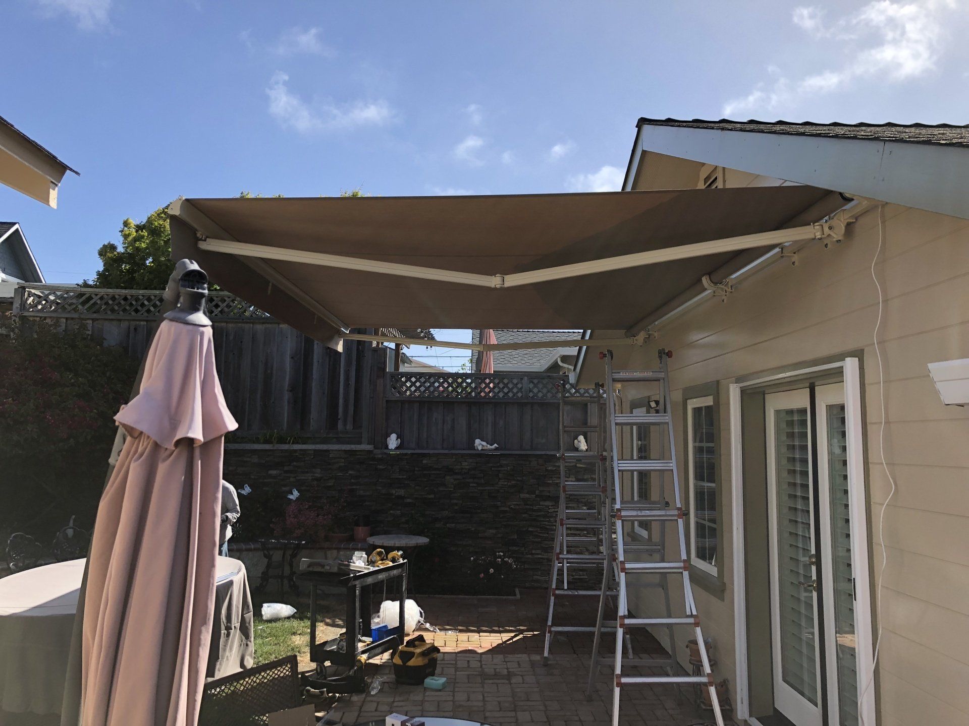 A house with an awning and an umbrella on the patio.