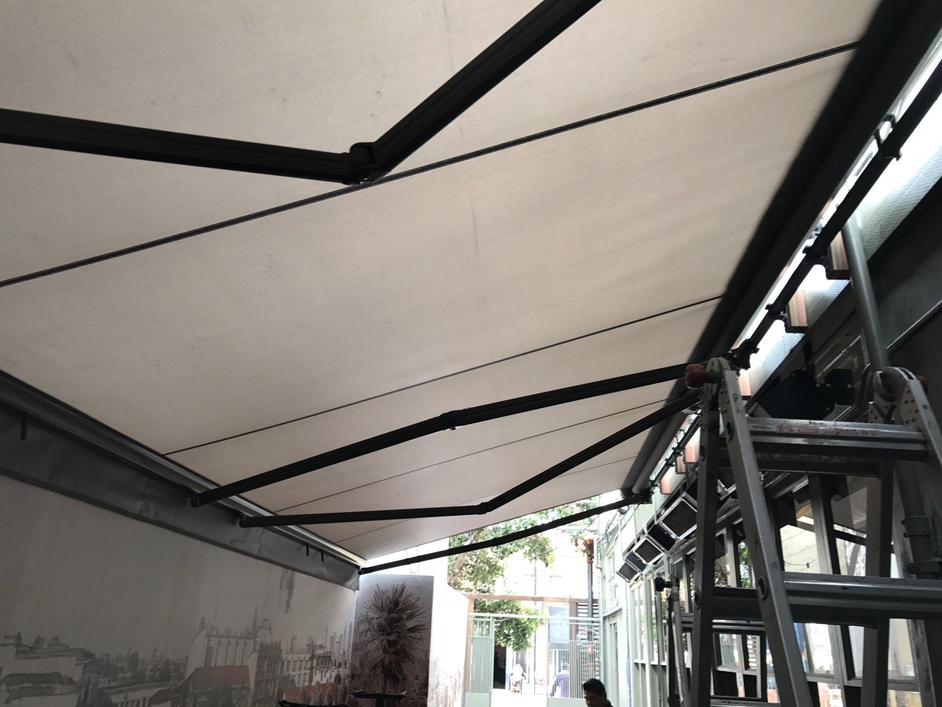 A person is standing on a ladder under an awning