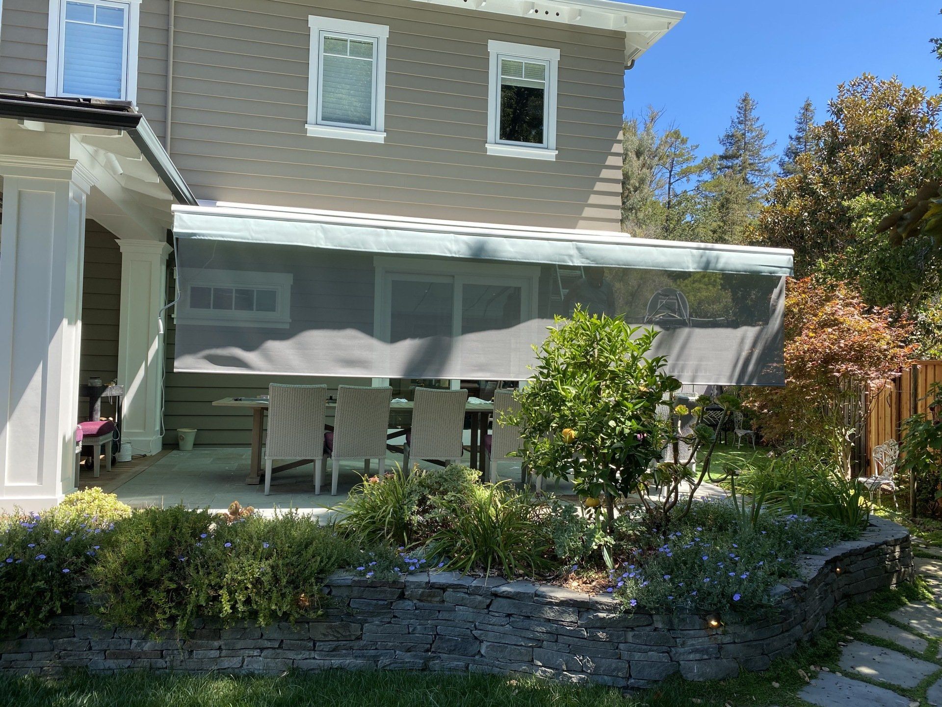 A house with a patio with a table and chairs under an awning.