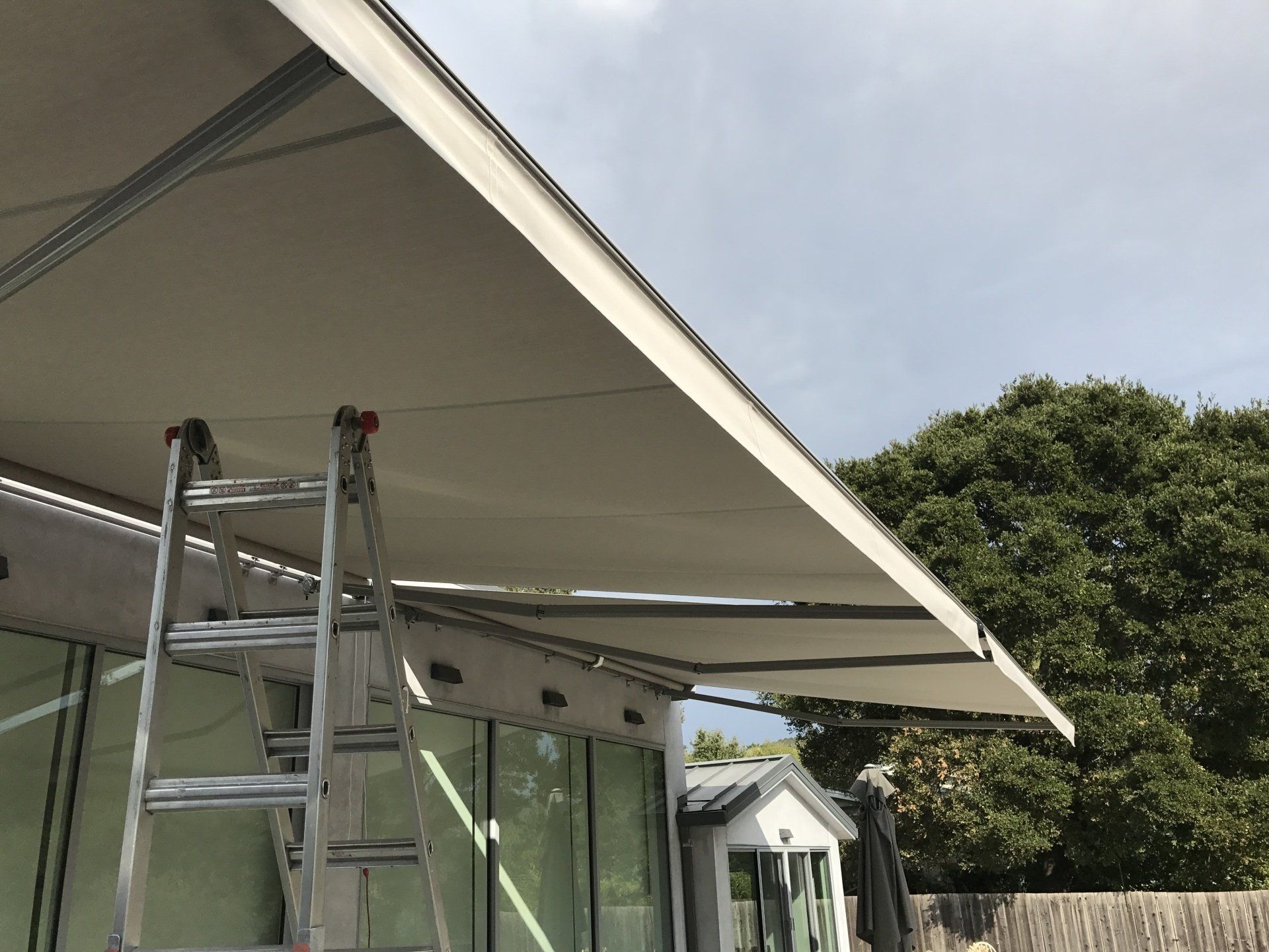A person is standing on a ladder under an awning.