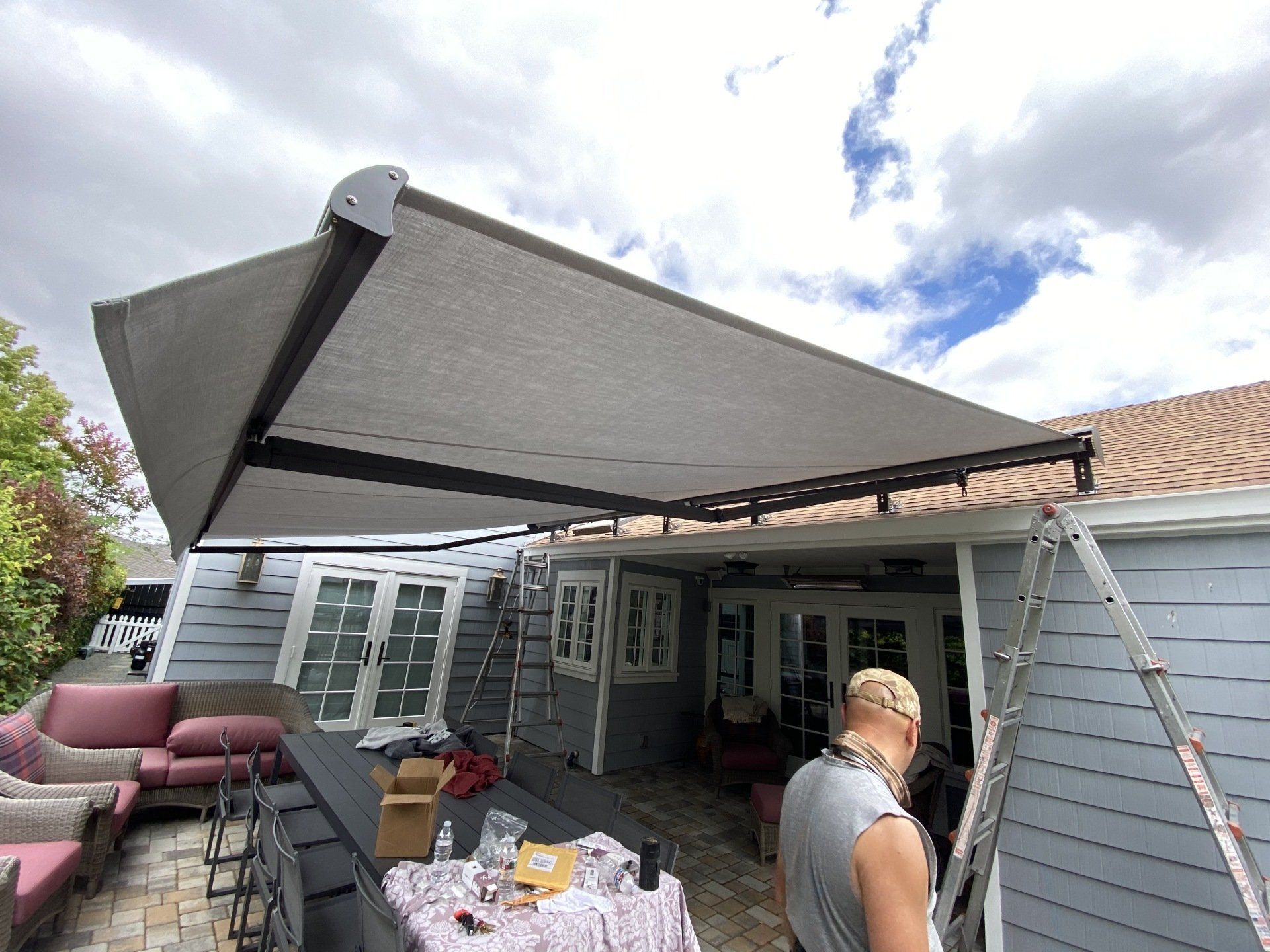A man is standing under an awning on the side of a house.