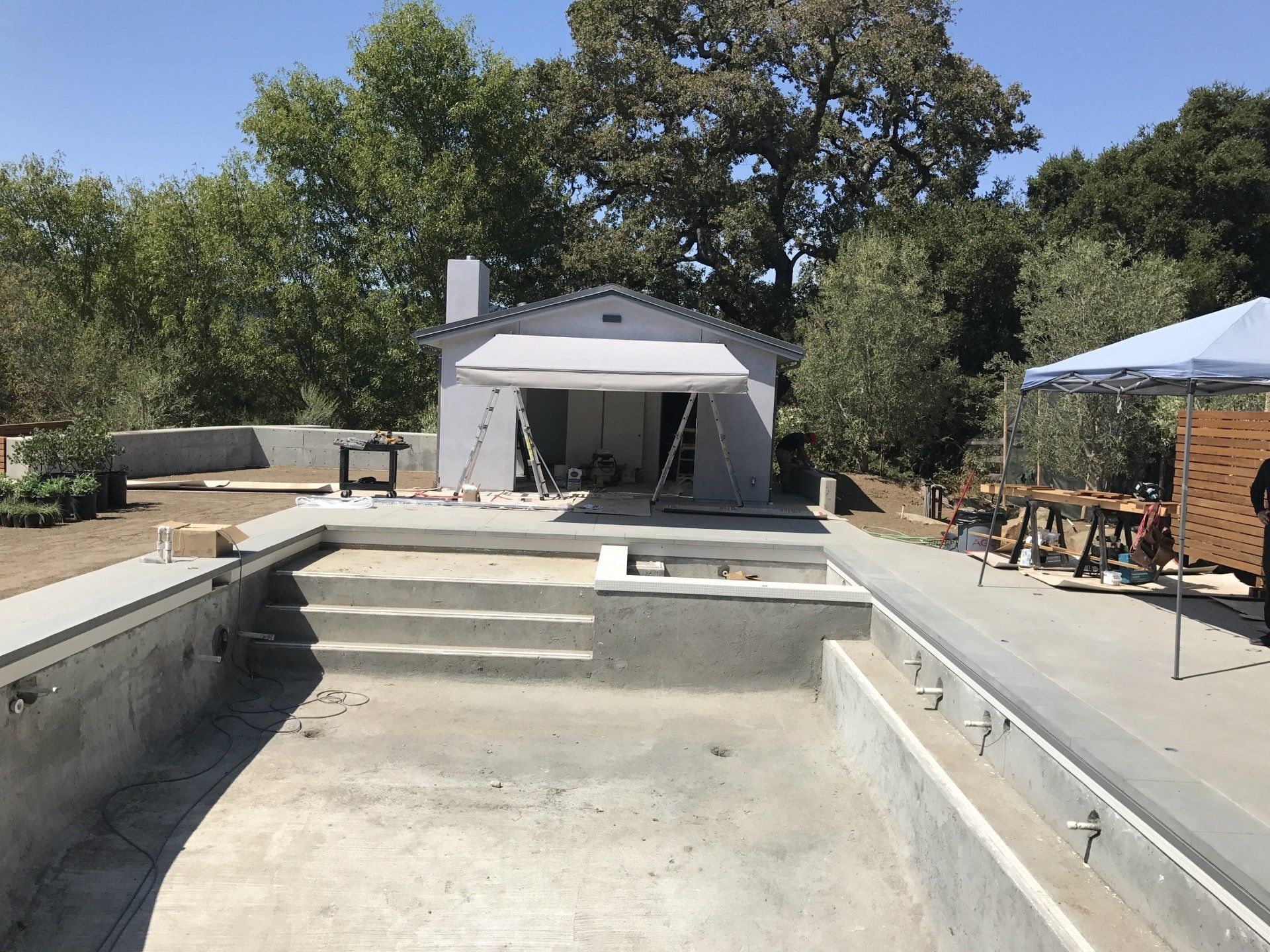 An empty swimming pool is being built in front of a house.