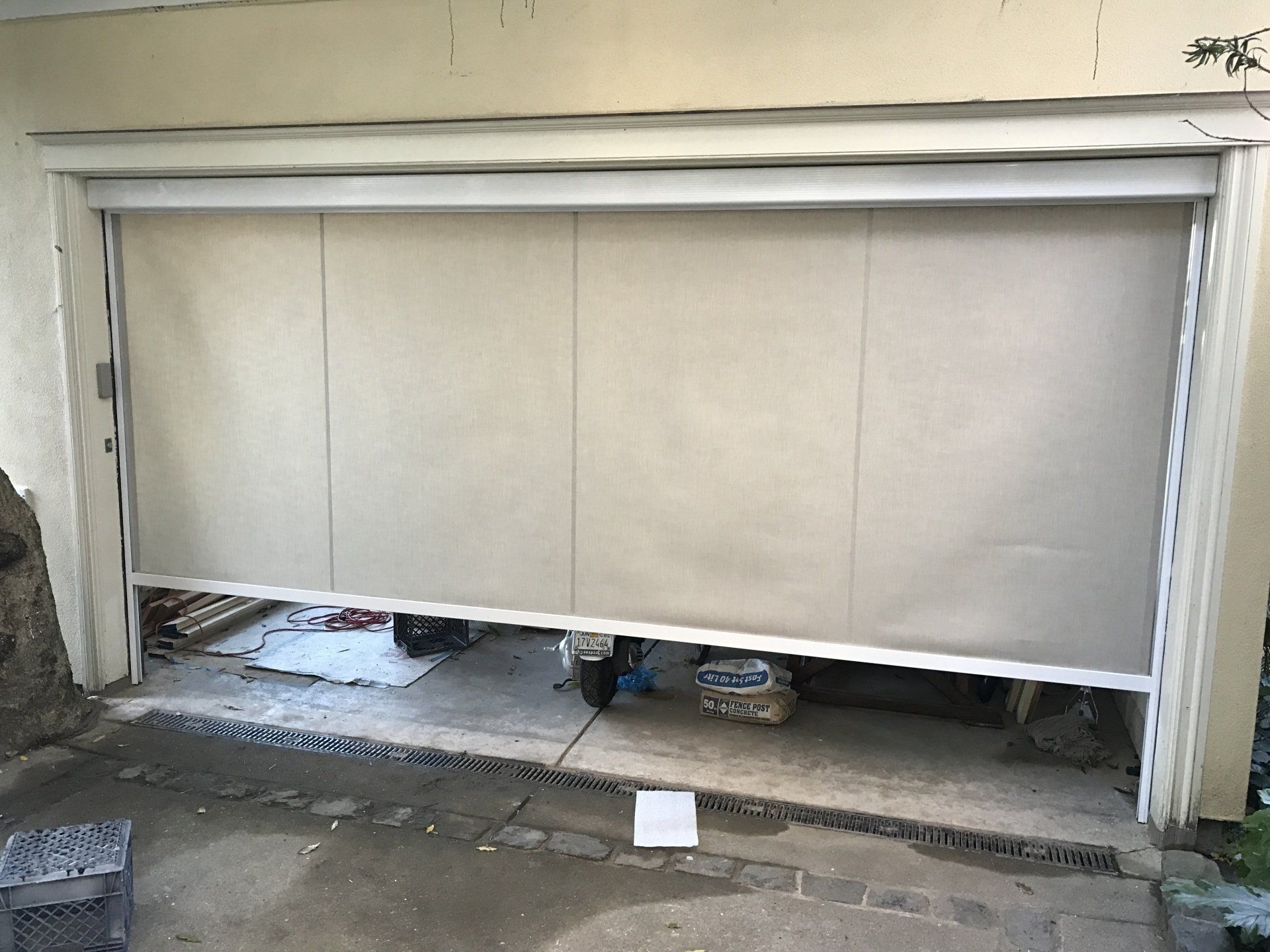 A garage door with a blind on it is open.