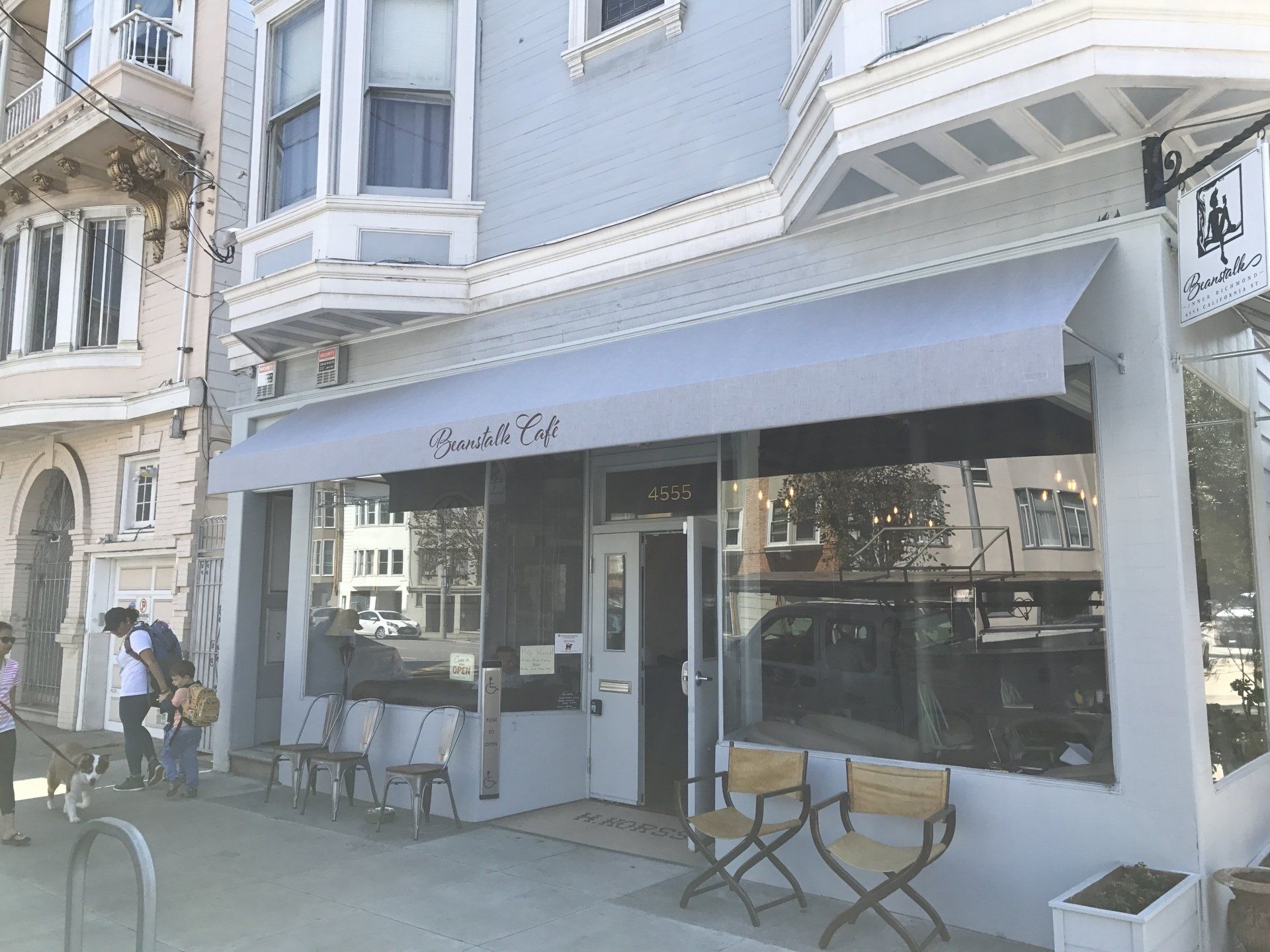 A store front with a white awning and chairs outside