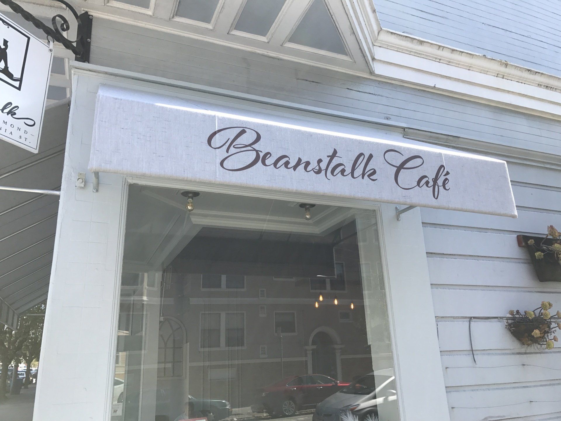 A white building with a sign that says beanstalk cafe