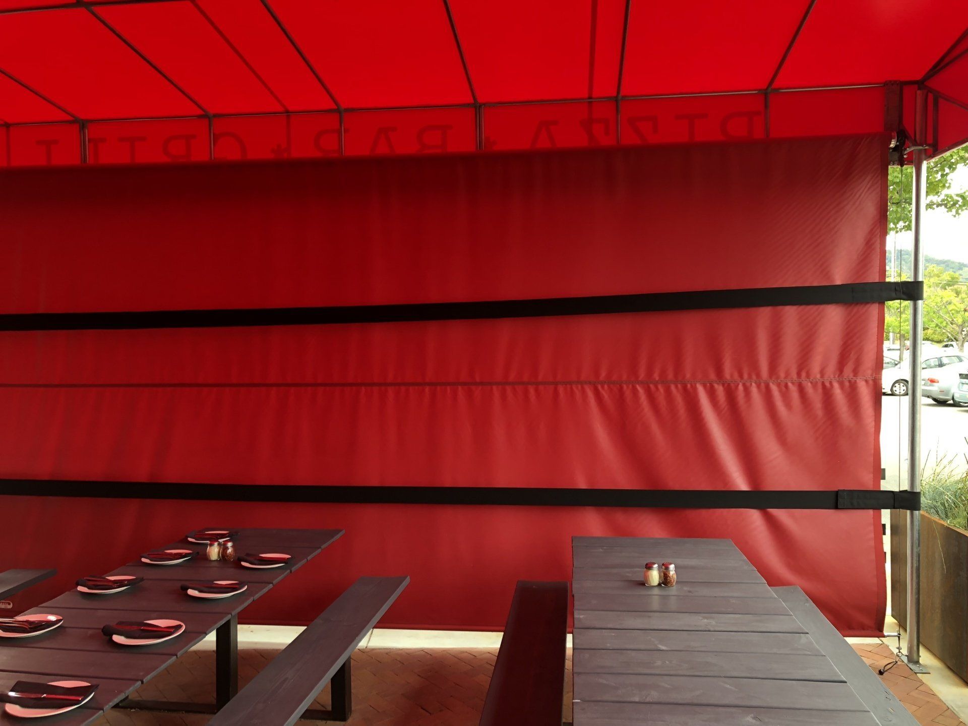 A restaurant with tables and benches under a red umbrella