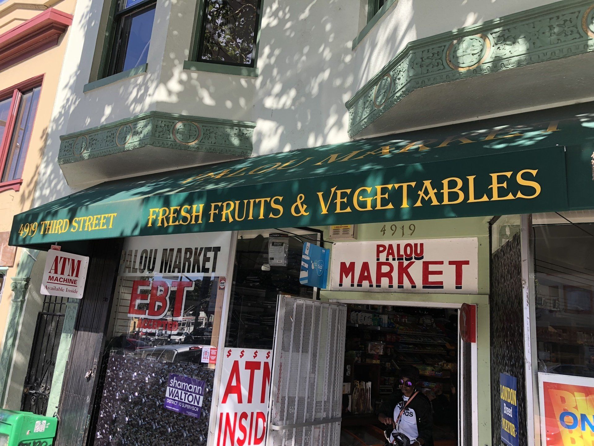 A store front with a green awning that says fresh fruits and vegetables
