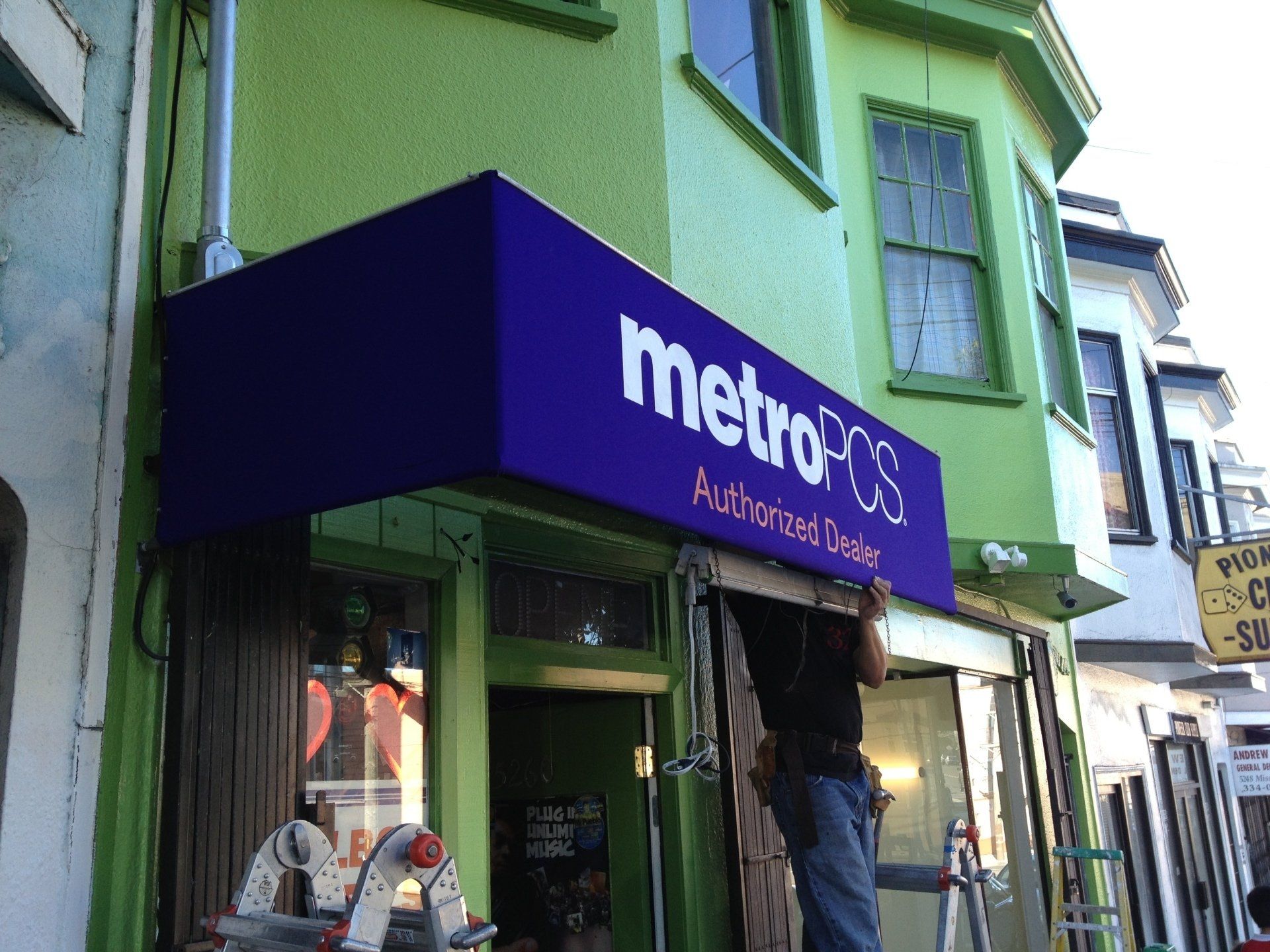 A green building with a purple sign that says metro on it