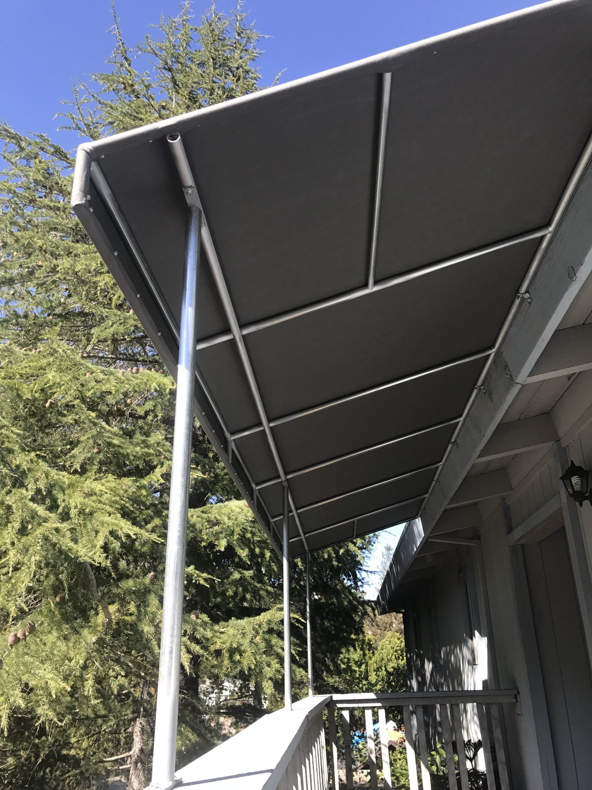 A porch with a canopy over it and trees in the background.