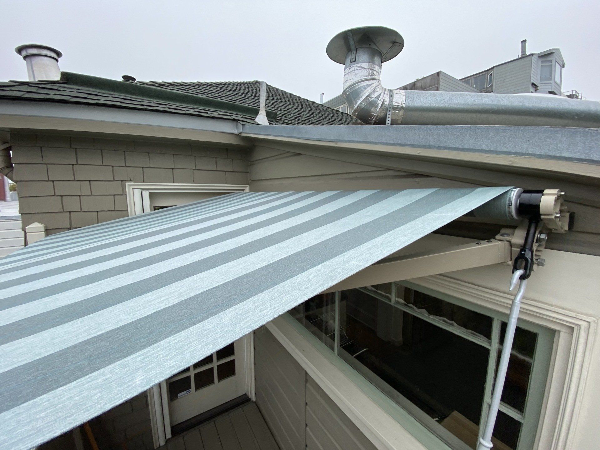 A striped awning is hanging from the roof of a house