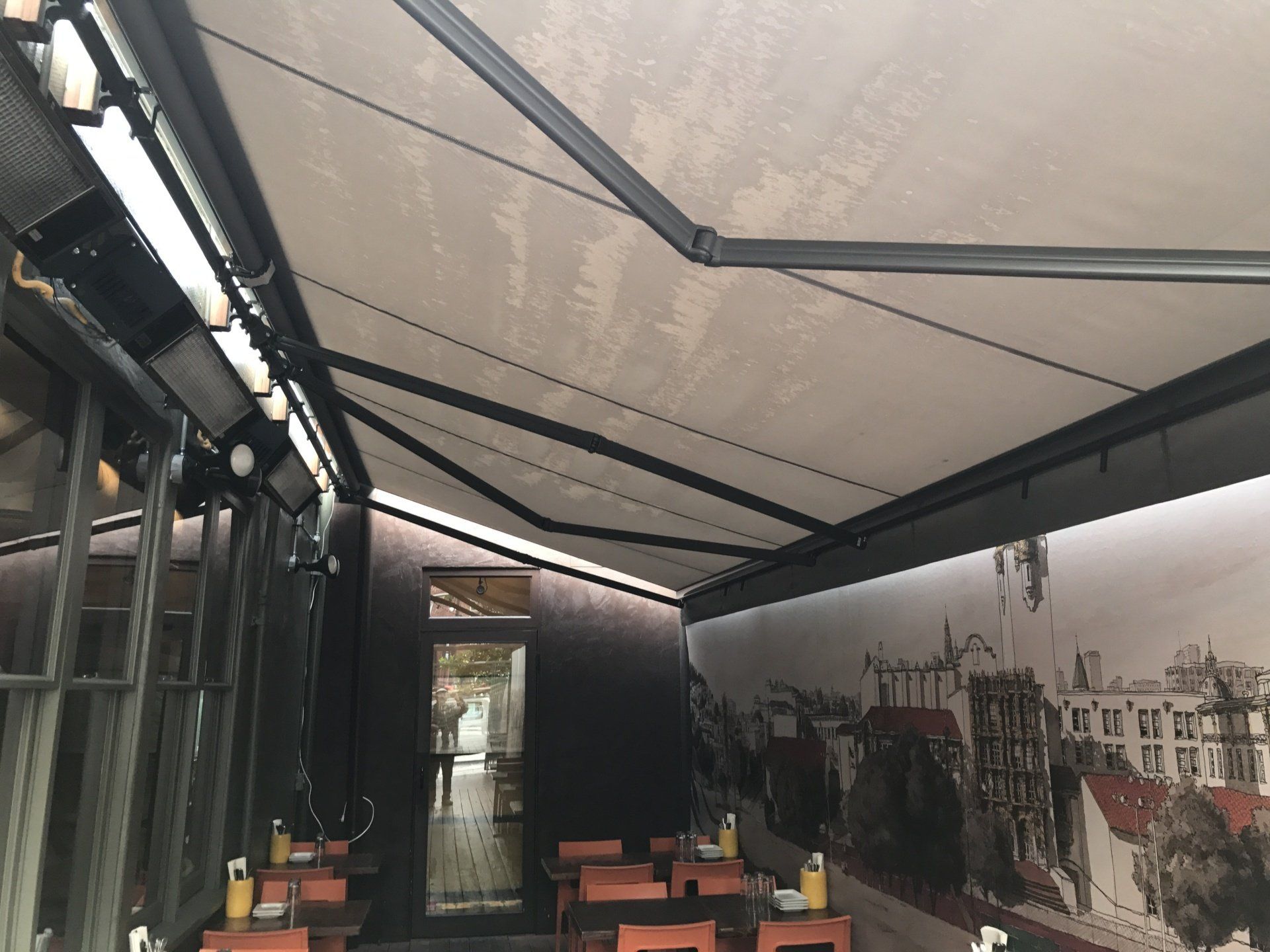 A restaurant with tables and chairs under an awning