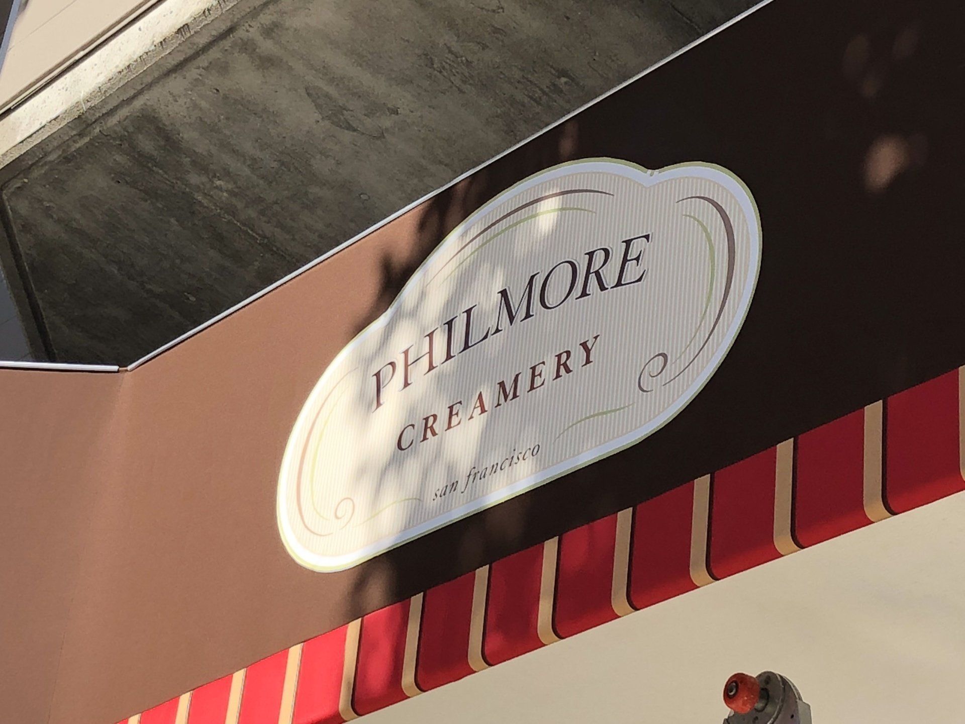 A sign for philmore creamery with a red awning