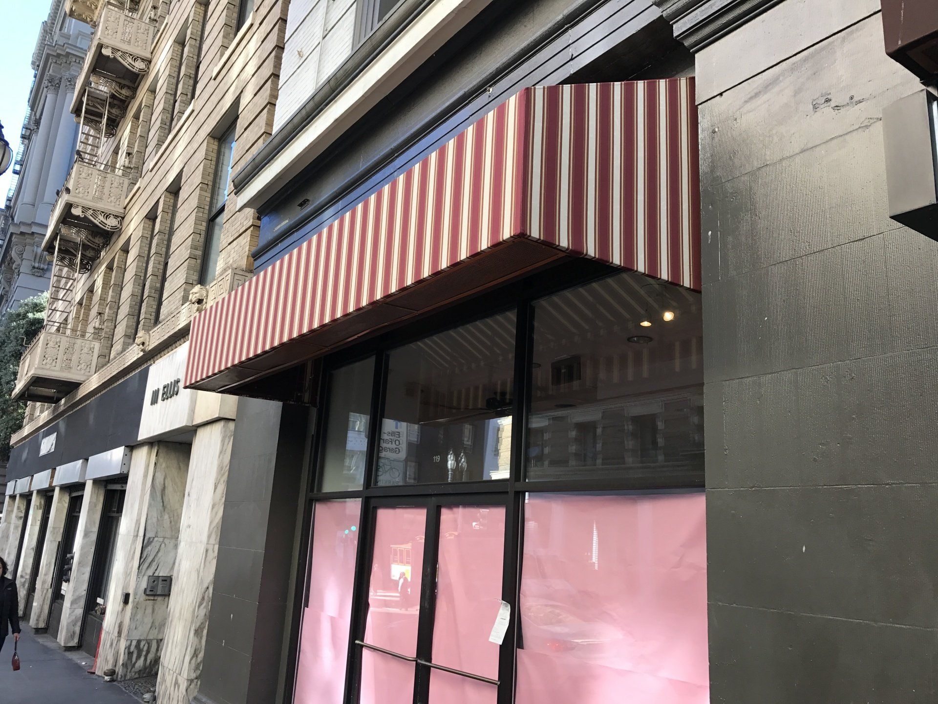 A store front with a red and white striped awning over it.