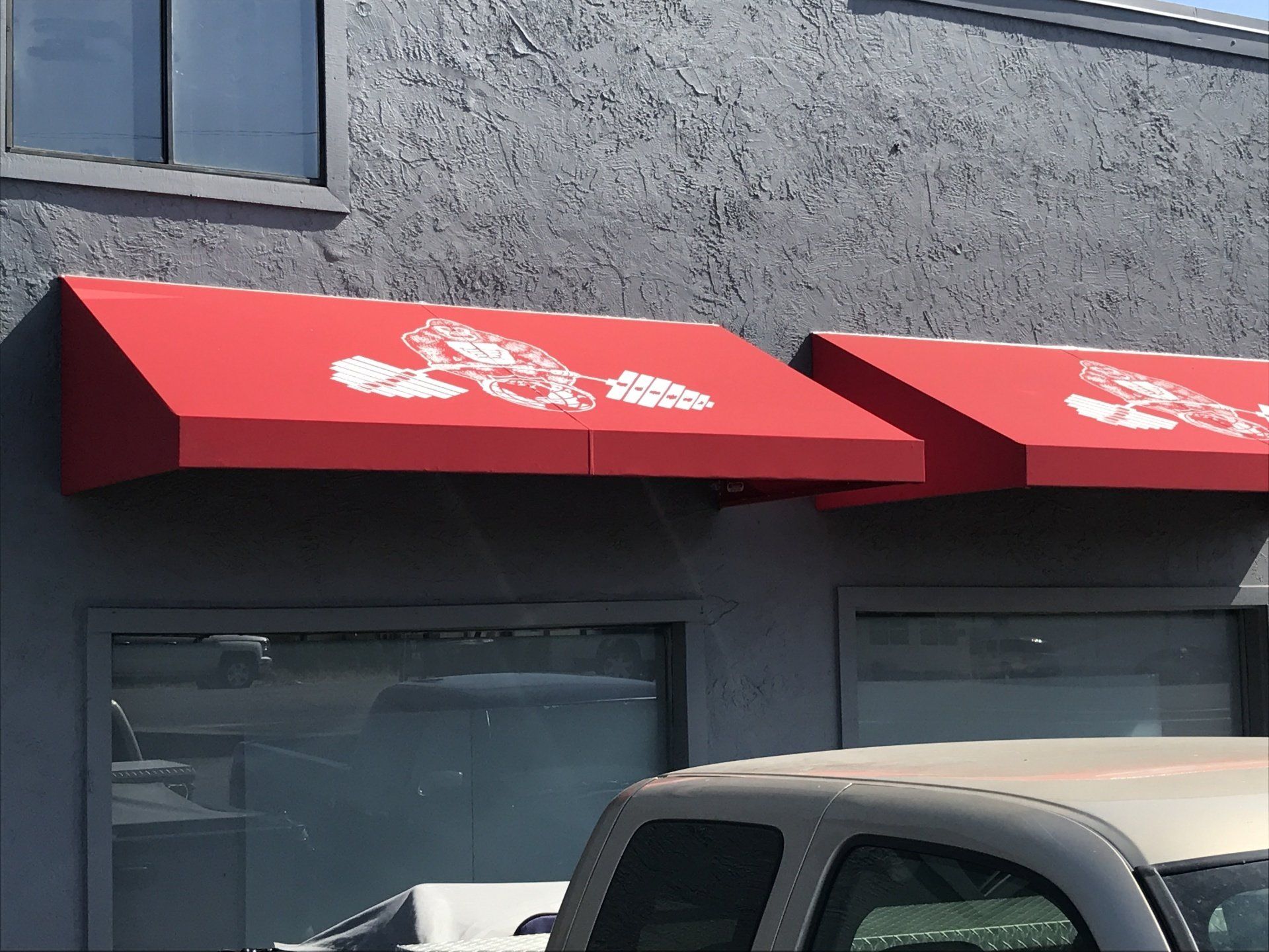 A truck is parked under a red awning on the side of a building.