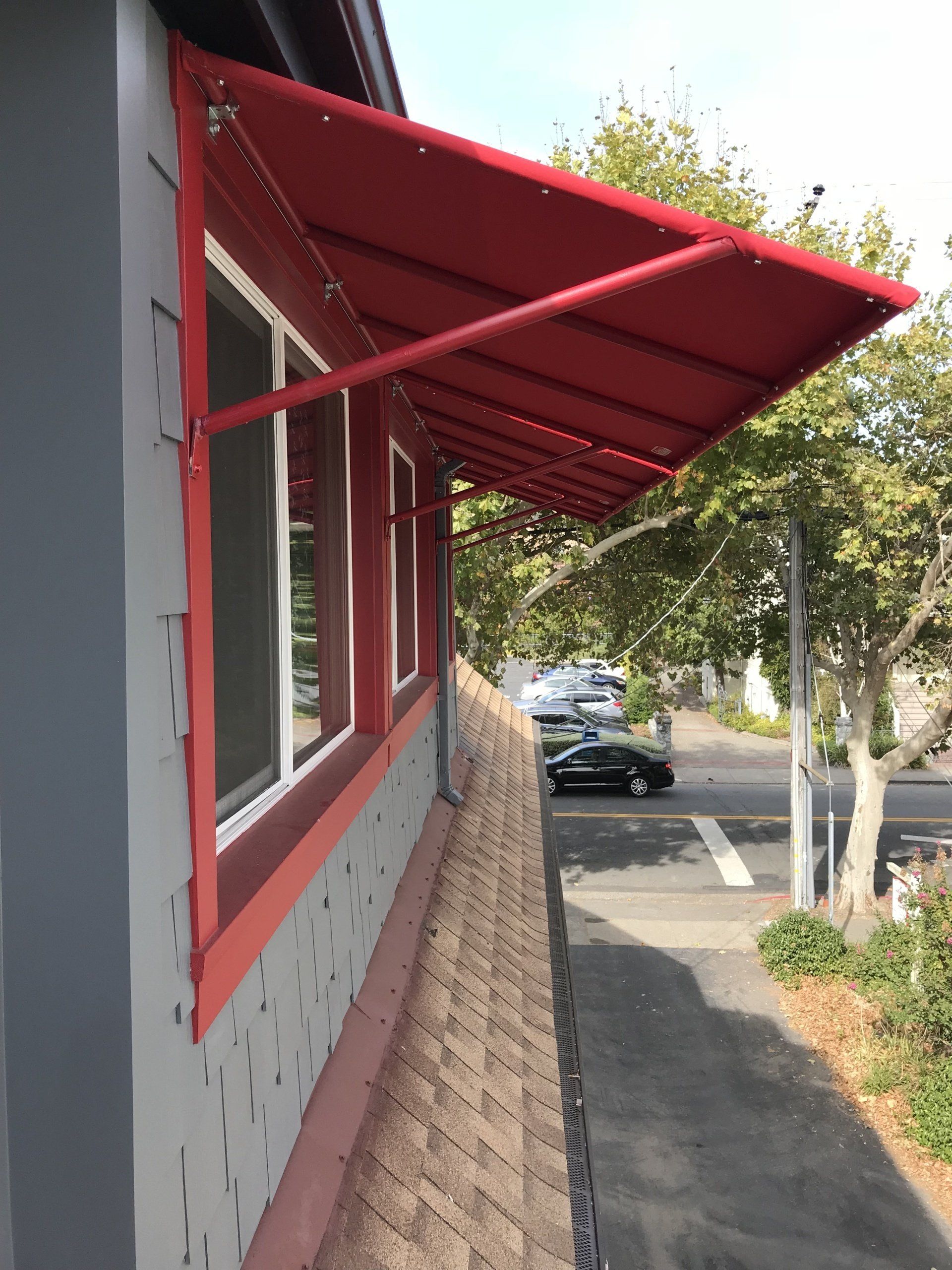 A red awning is hanging over a window on the side of a building.