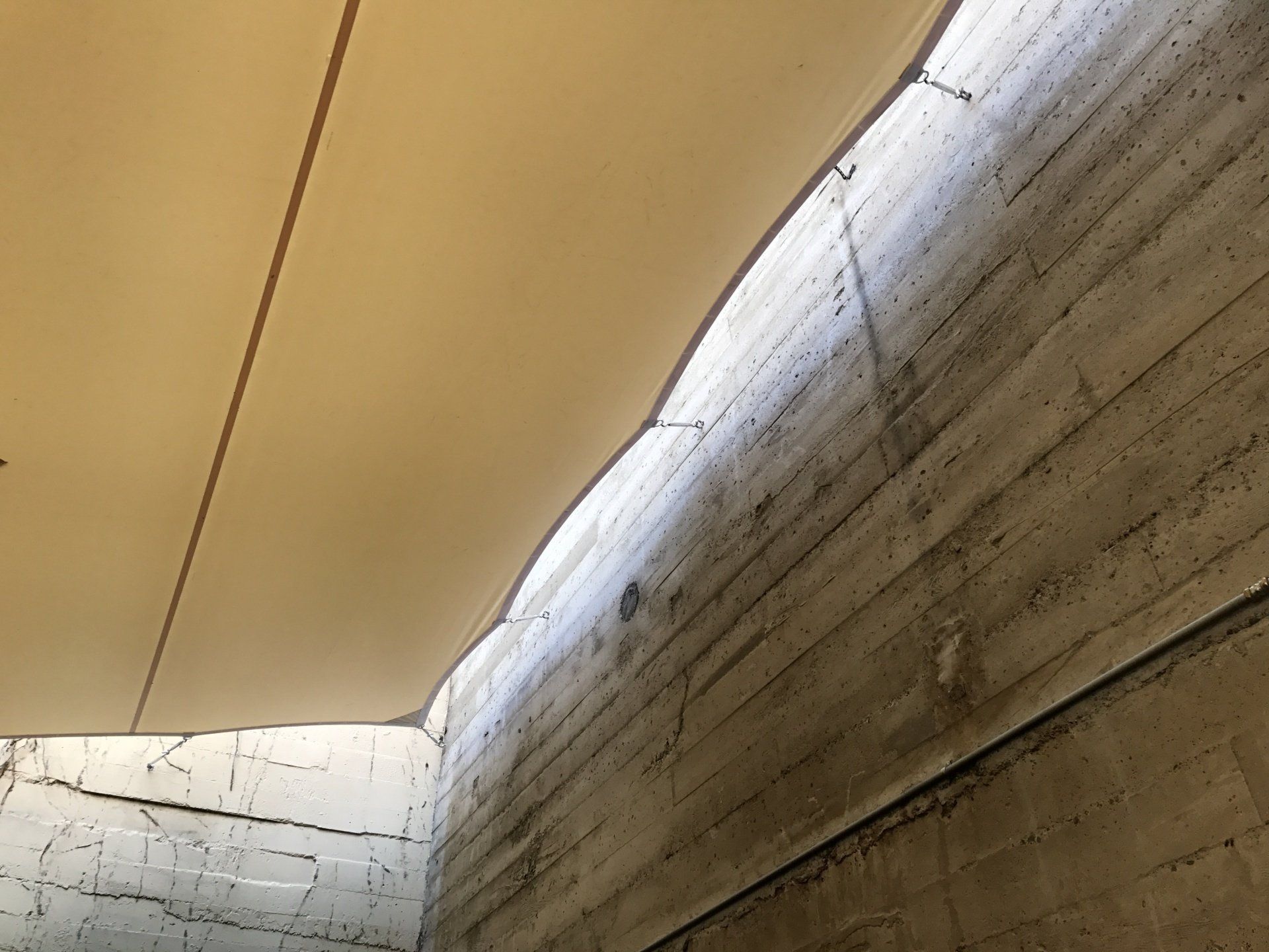 A concrete wall with a white umbrella hanging from it