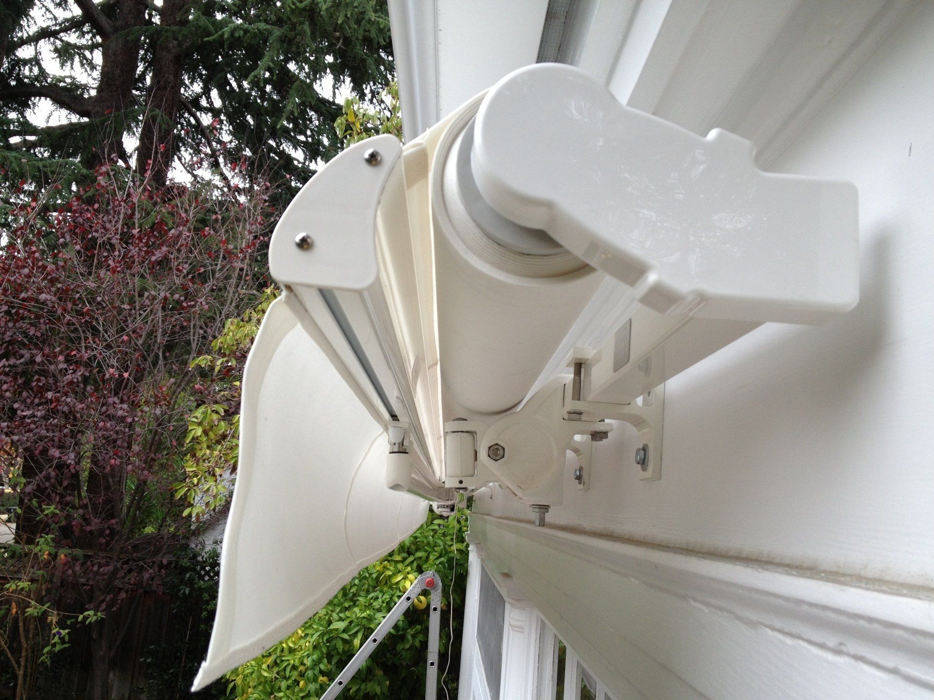 A white awning is hanging on the side of a white building.
