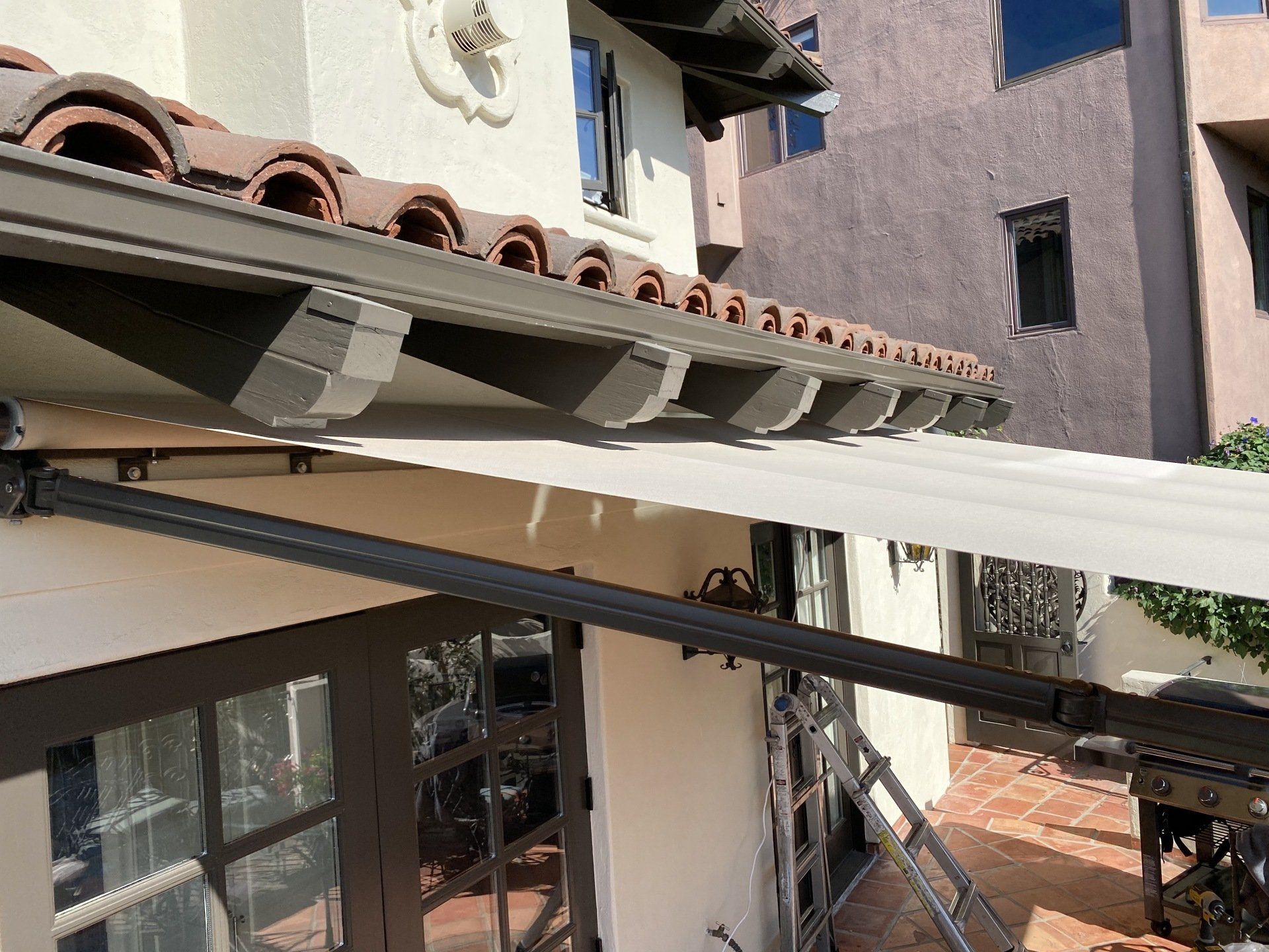 A white awning is being installed on the roof of a house.