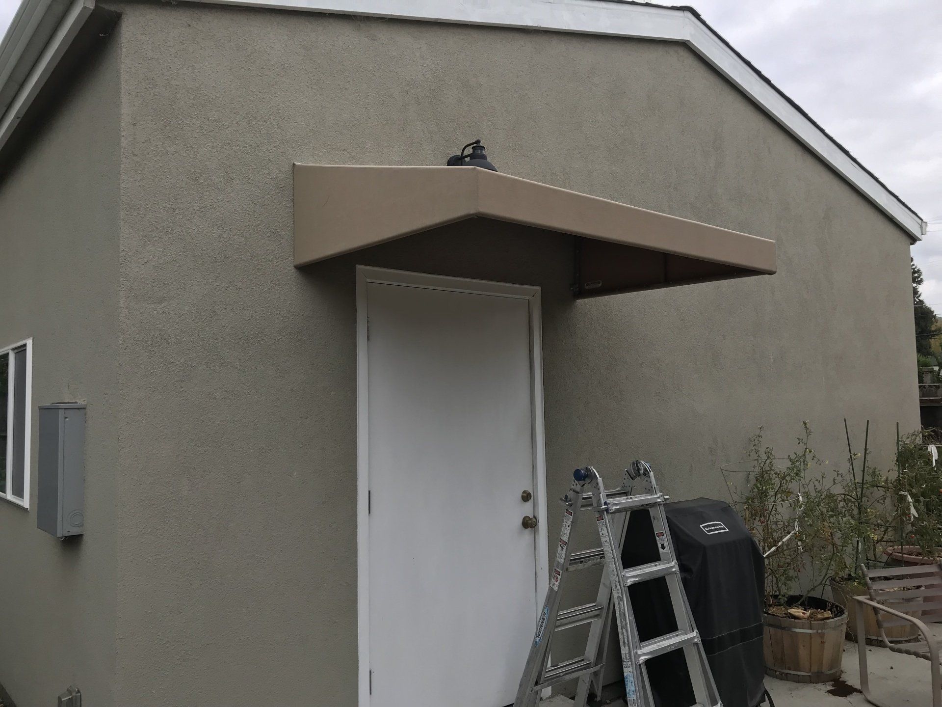 A ladder is sitting on the side of a building next to a door.