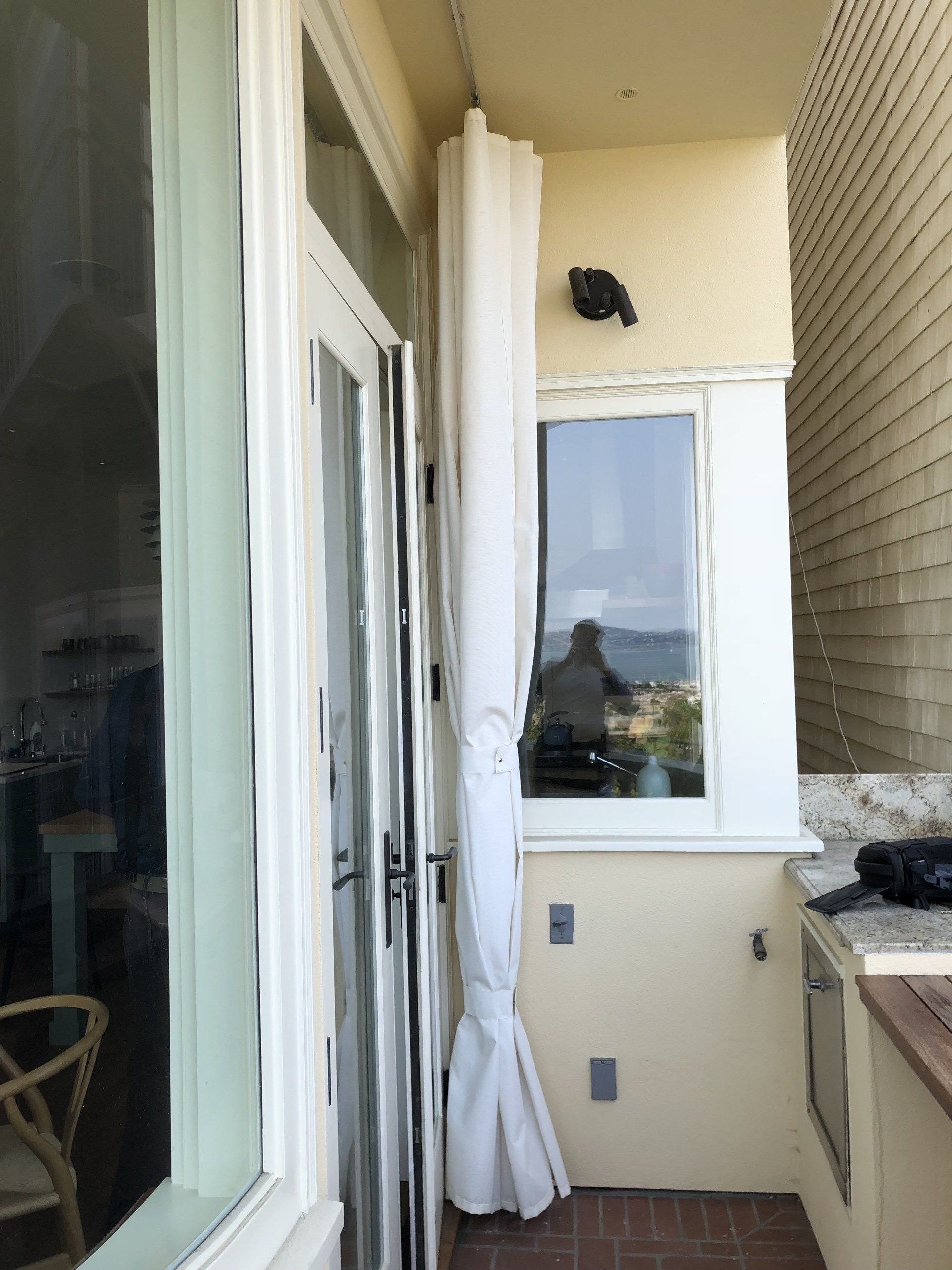 A balcony with a white curtain and a window