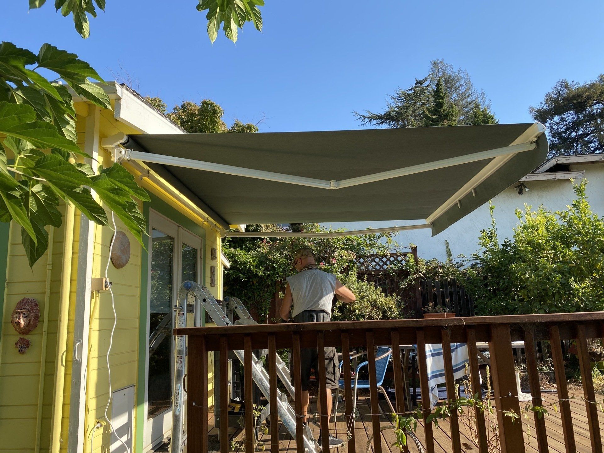 A man is standing on a deck under an awning.