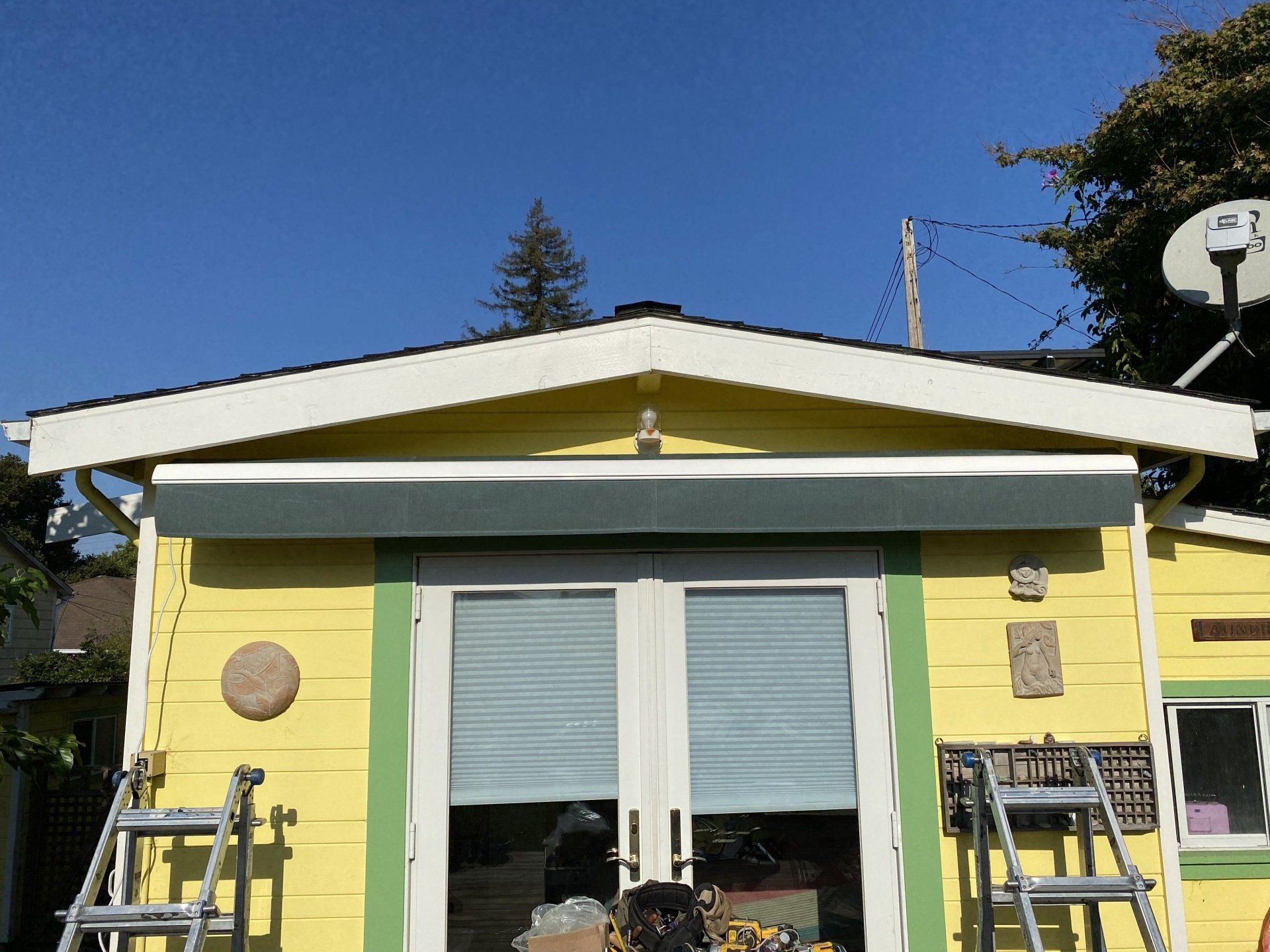 A yellow and green house with a ladder in front of it